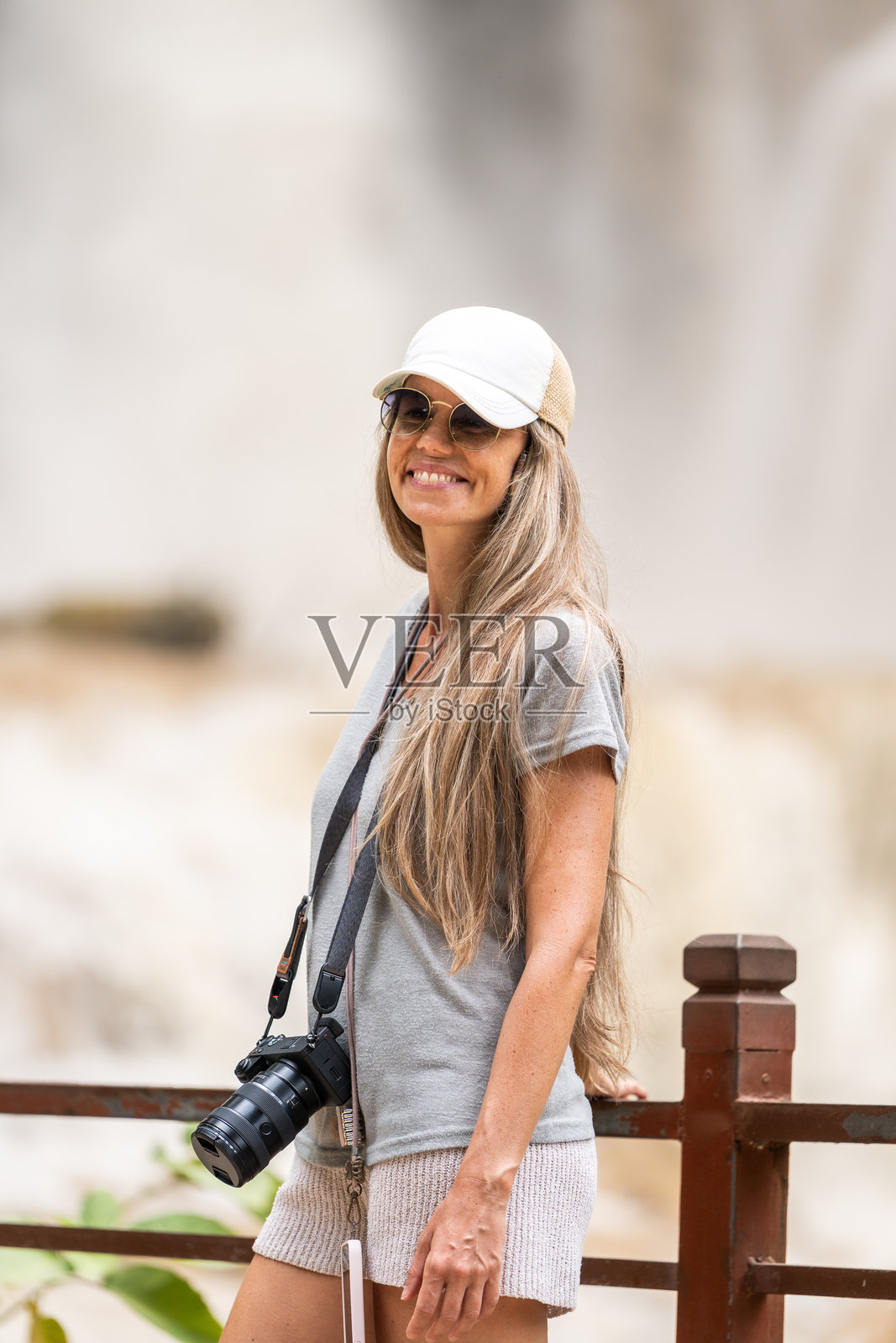 笑容满面的女性，手持相机，享受着旅行和自然风光照片摄影图片