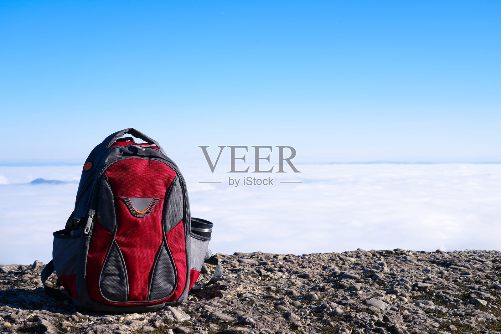 背包放置在岩石地形上，背景是广阔的白天天空和云朵照片摄影图片