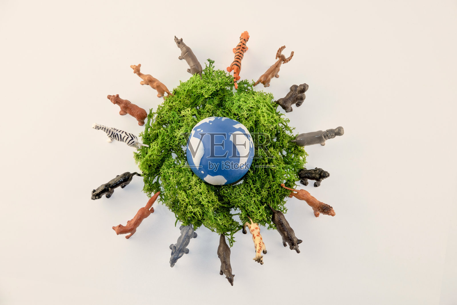 玩具动物们围绕着一个蓝色的小地球，背景是鲜绿色的苔藓，生动地描绘了自然世界与野生动物保护的趣味景象照片摄影图片