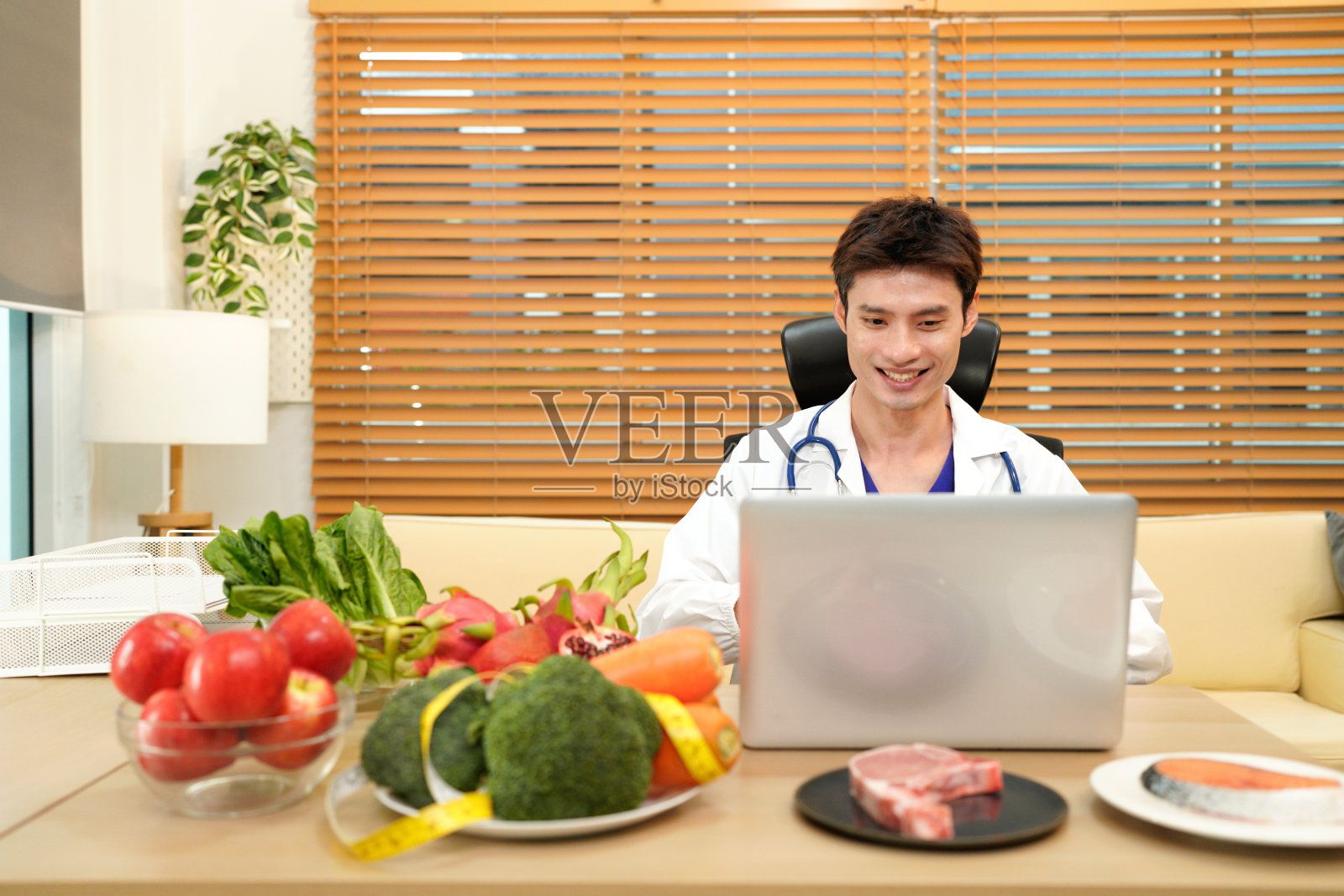 营养师在电脑前工作，并向病人提供咨询，桌上有健康的水果和蔬菜，体现了正确的营养和饮食理念照片摄影图片