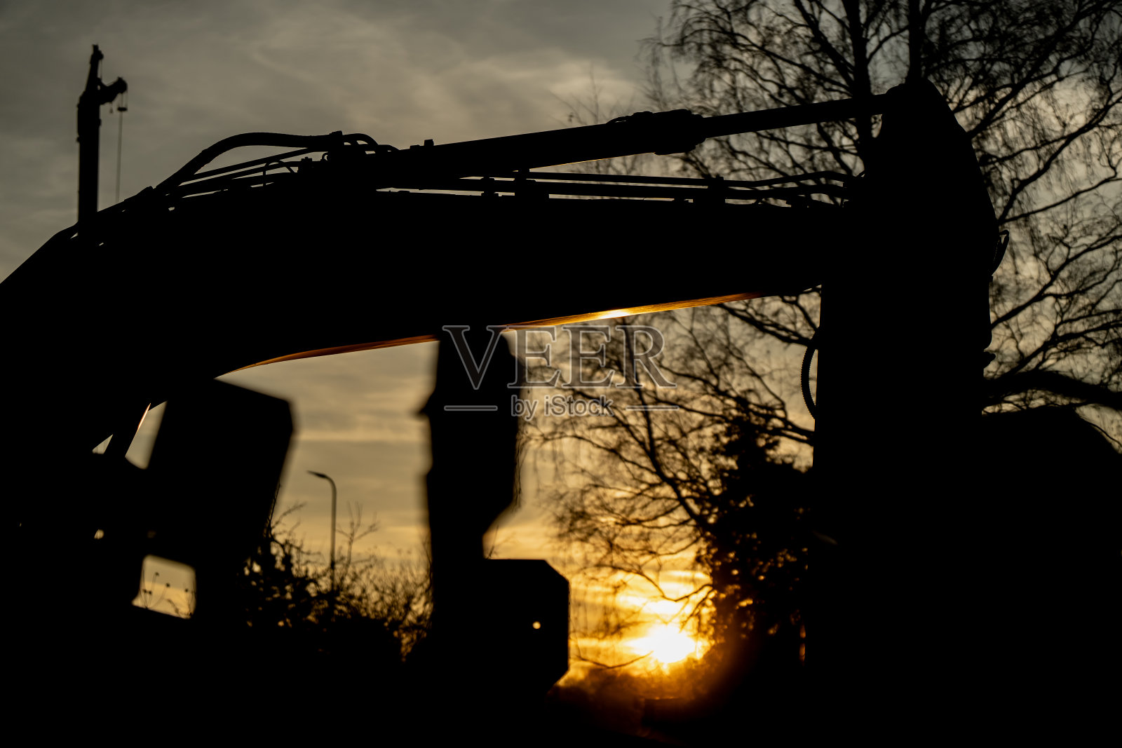 日落时分挖掘机手臂和液压臂的剪影，代表建筑行业的机械、工程技术以及在城市或工业工地上重型设备的运作照片摄影图片