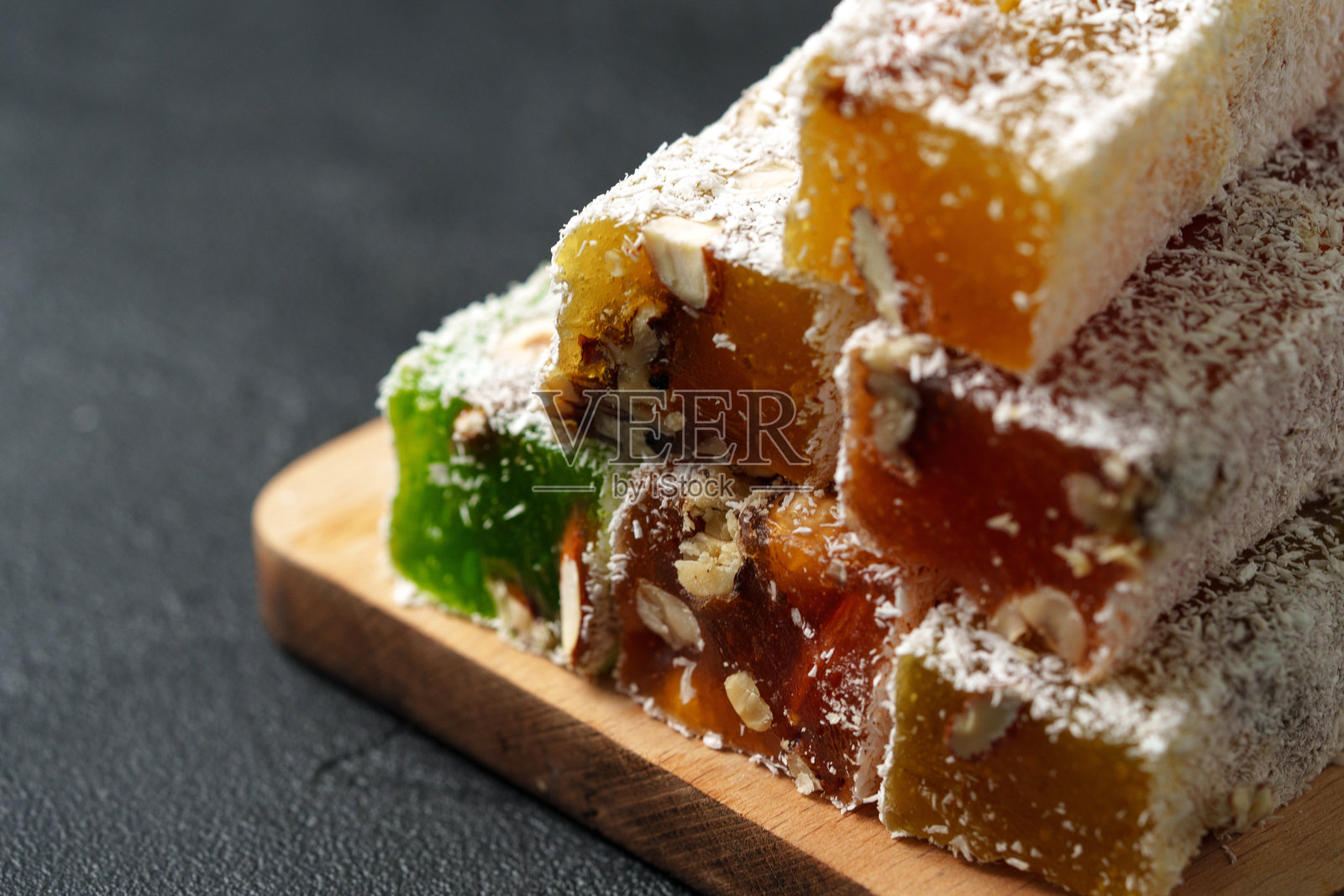 色彩缤纷的土耳其软糖堆叠在木板上，背景带有纹理，并撒上了椰丝照片摄影图片