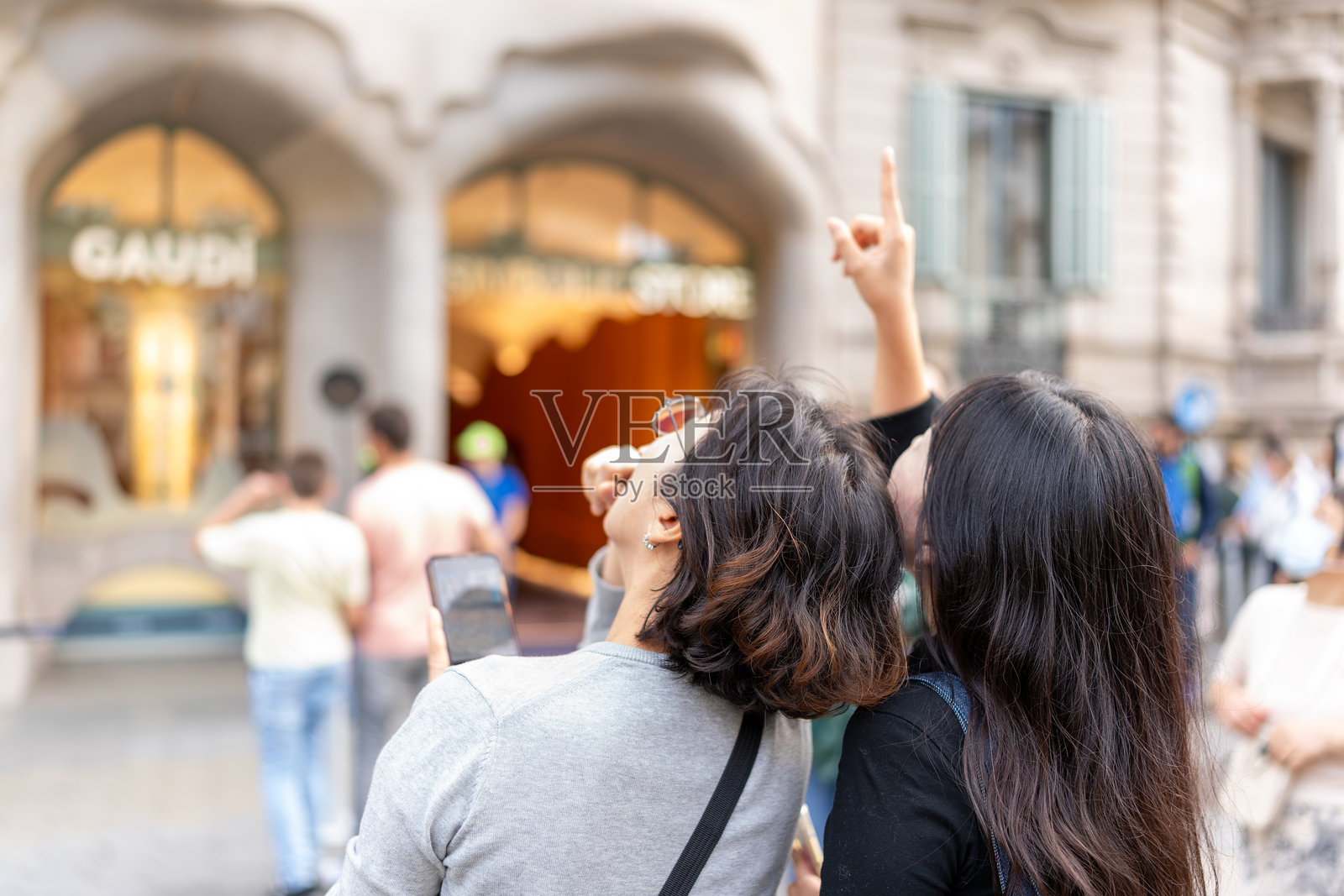 游客在西班牙巴塞罗那指向历史悠久的巴特罗之家建筑照片摄影图片