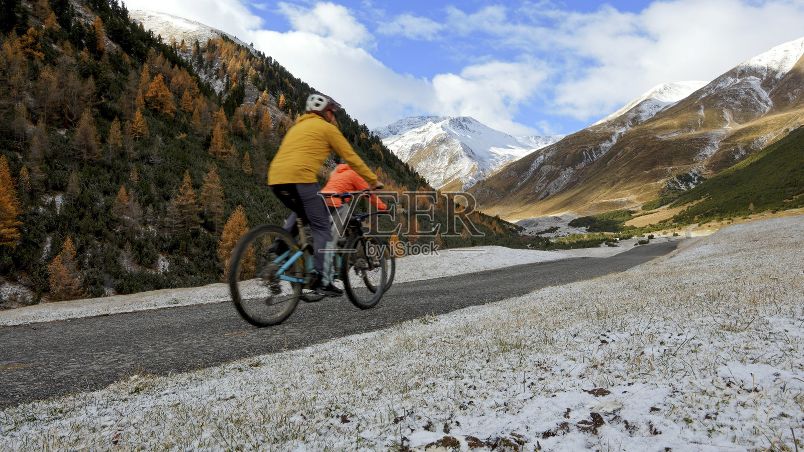 一对年长的夫妇骑着电动自行车沿着乡村小路在山间行驶照片摄影图片