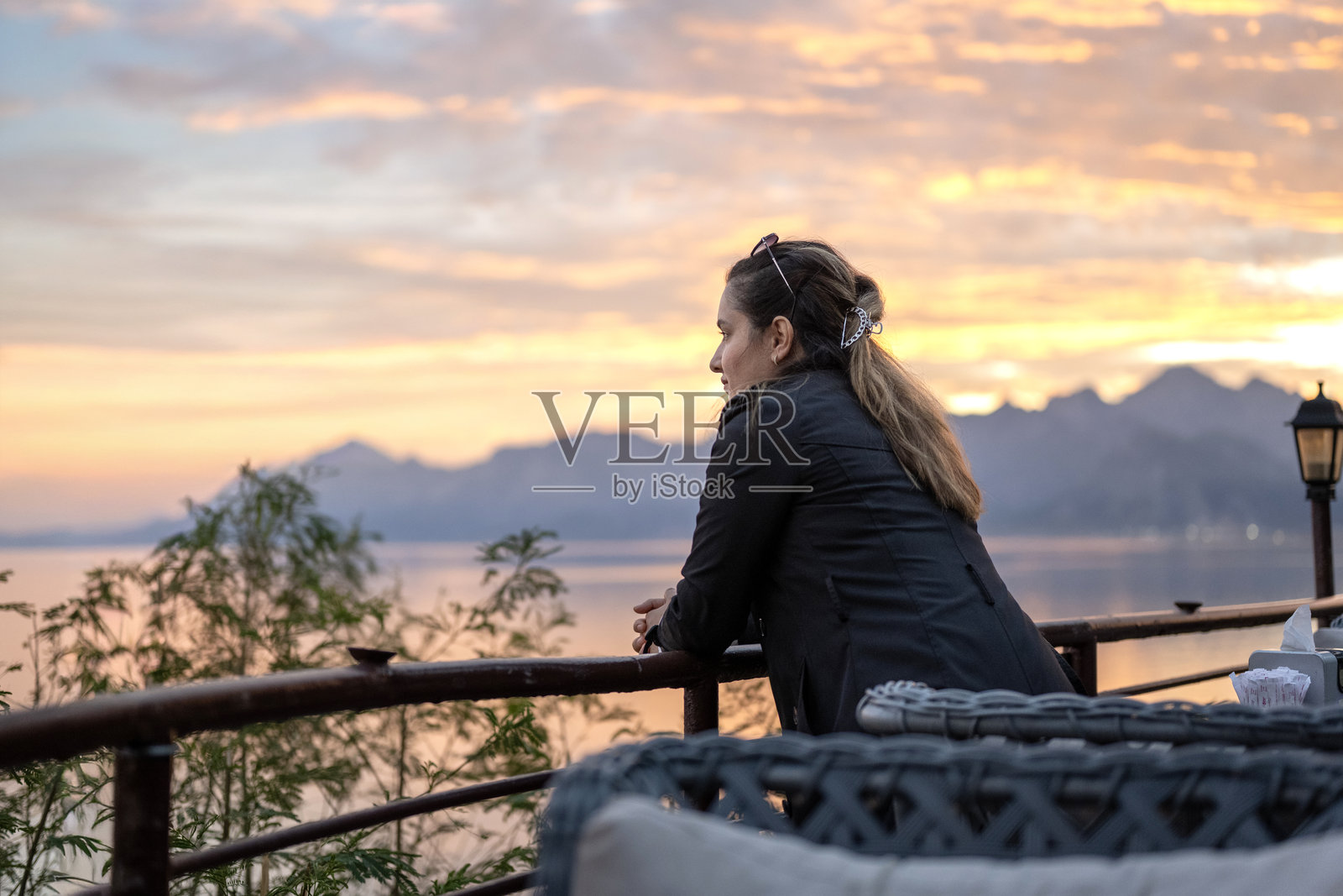 年轻女子在日落时分悠闲地在阳台上放松照片摄影图片