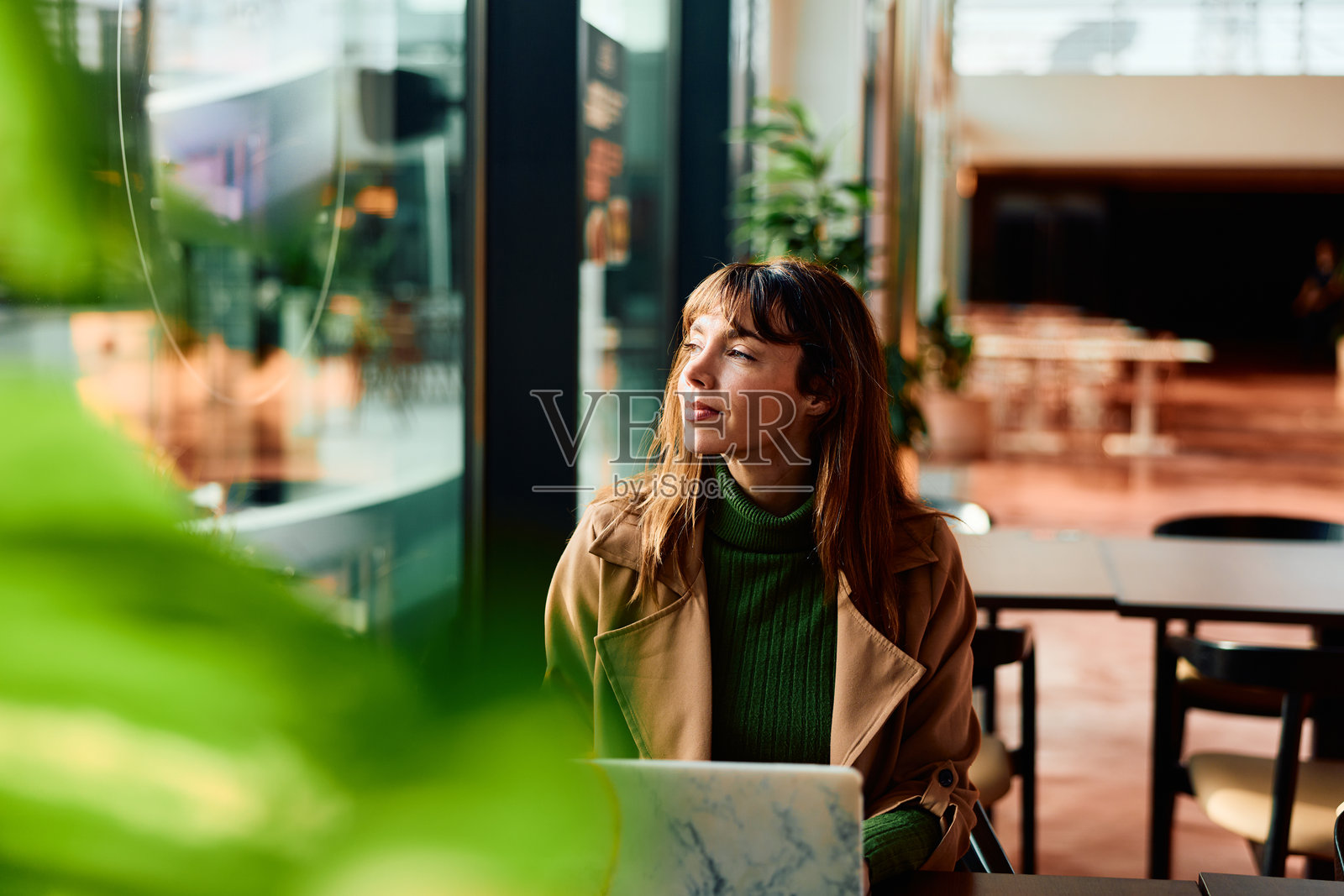 女子在咖啡馆远程工作，若有所思地望向远方照片摄影图片