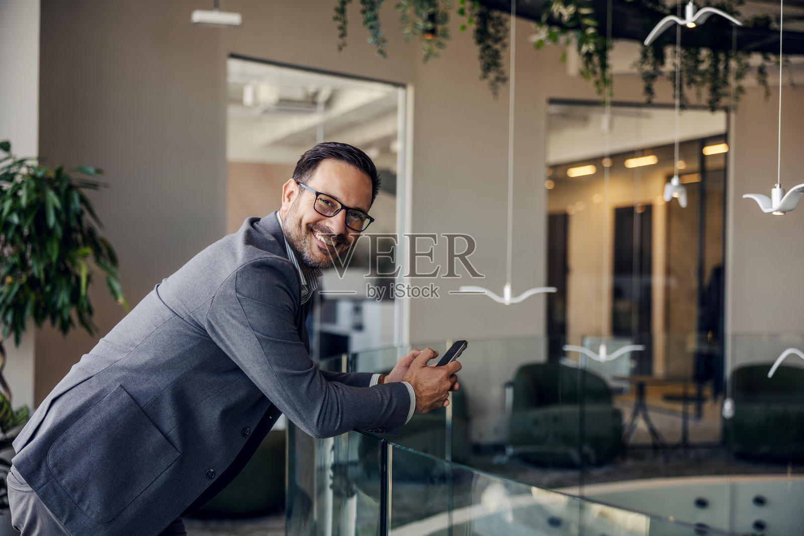 成熟的成年商人在现代办公室里微笑着使用手机照片摄影图片