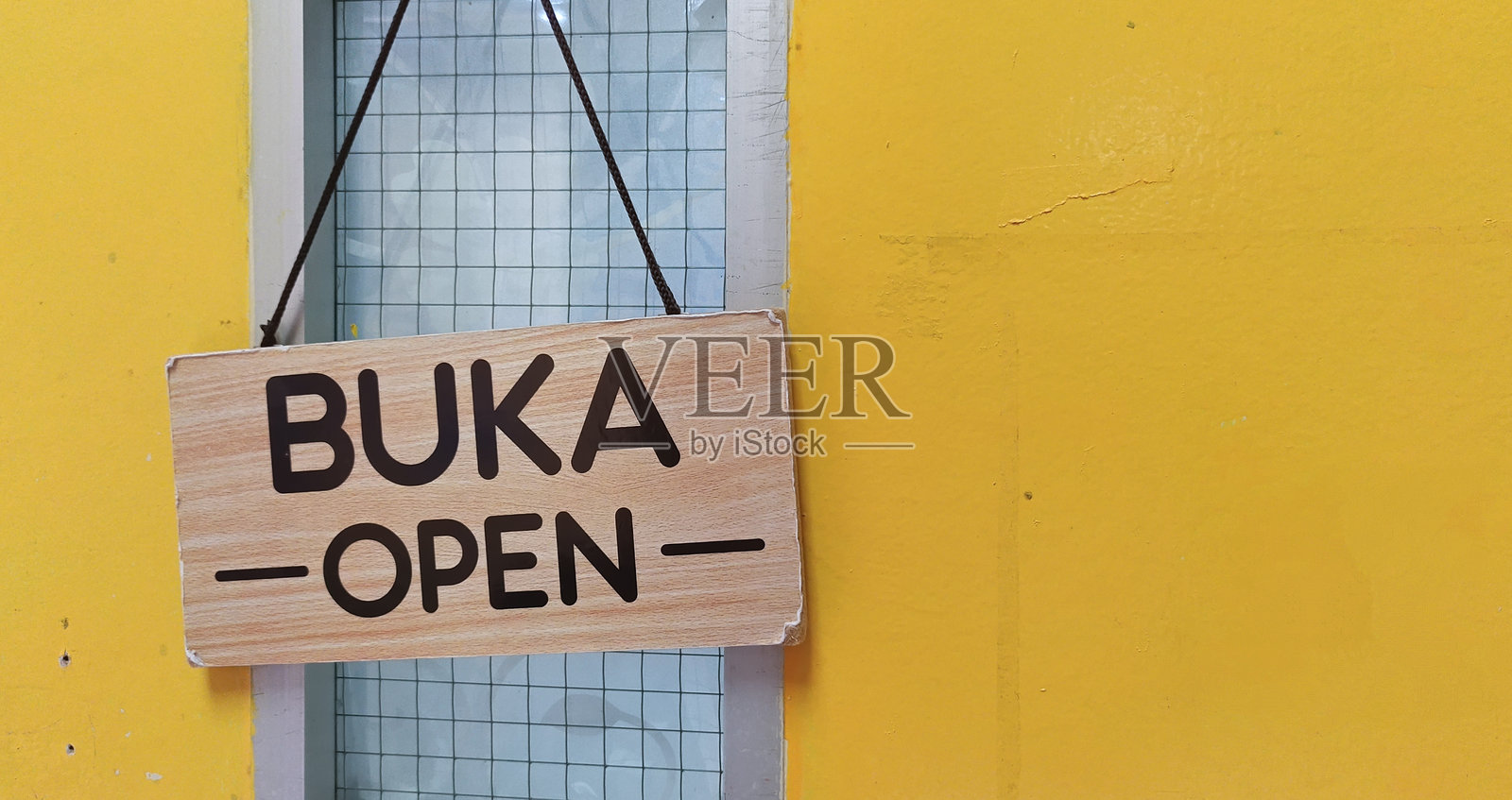 今日营业，欢迎顾客光临，明亮的黄墙上挂着‘营业中’的招牌。照片摄影图片