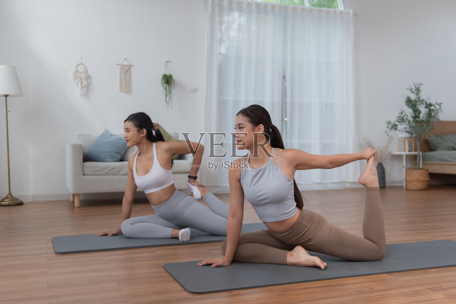 身穿运动服的年轻亚洲女性在家中的客厅进行锻炼和瑜伽练习，运动与休闲概念。照片摄影图片