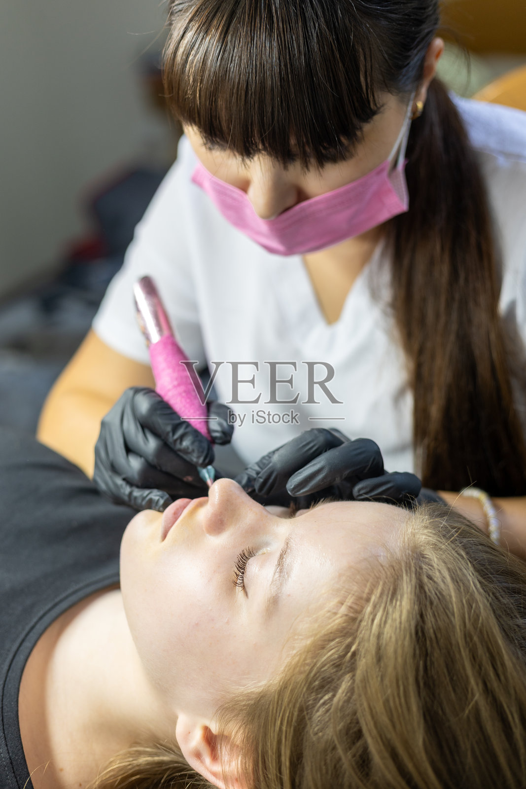 专家在美容护理过程中进行持久唇部纹绣，以实现持久的妆效照片摄影图片