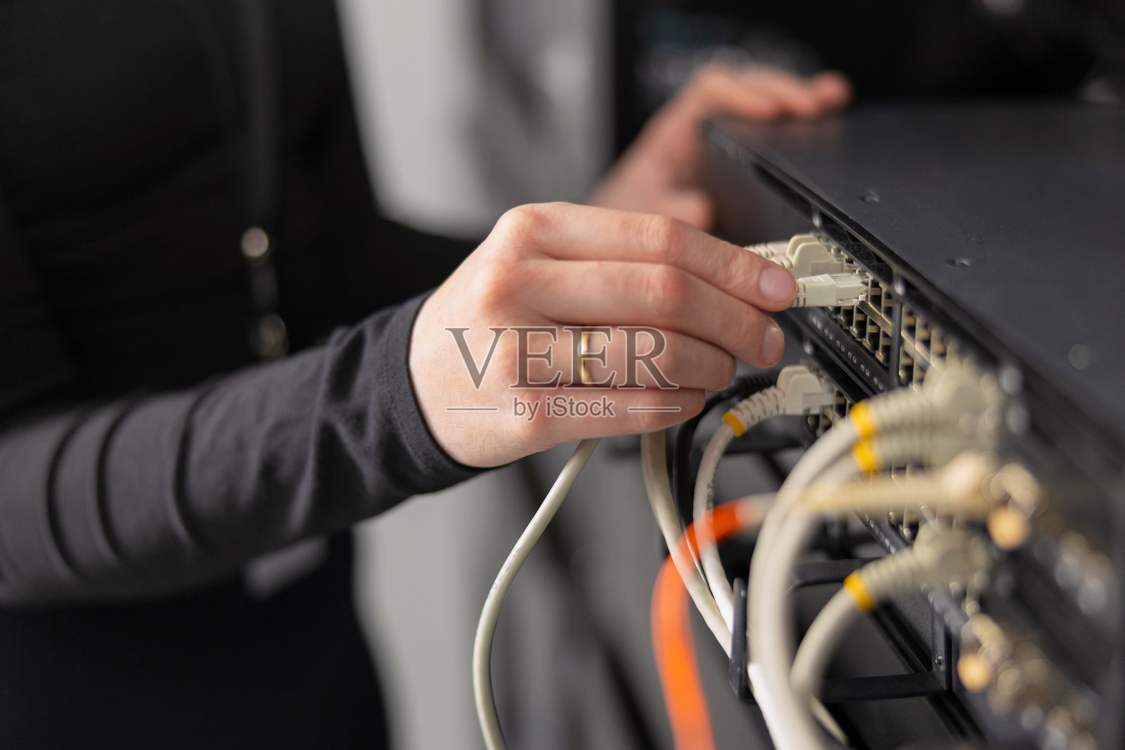 女性IT技术人员在数据中心连接网络线缆到服务器机架进行维护照片摄影图片