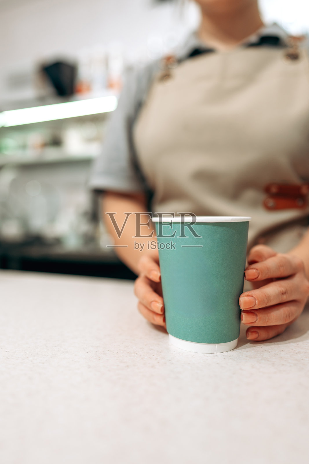 咖啡师在咖啡馆里，在下午的阳光下，在柜台上用一个绿色的杯子递送咖啡照片摄影图片