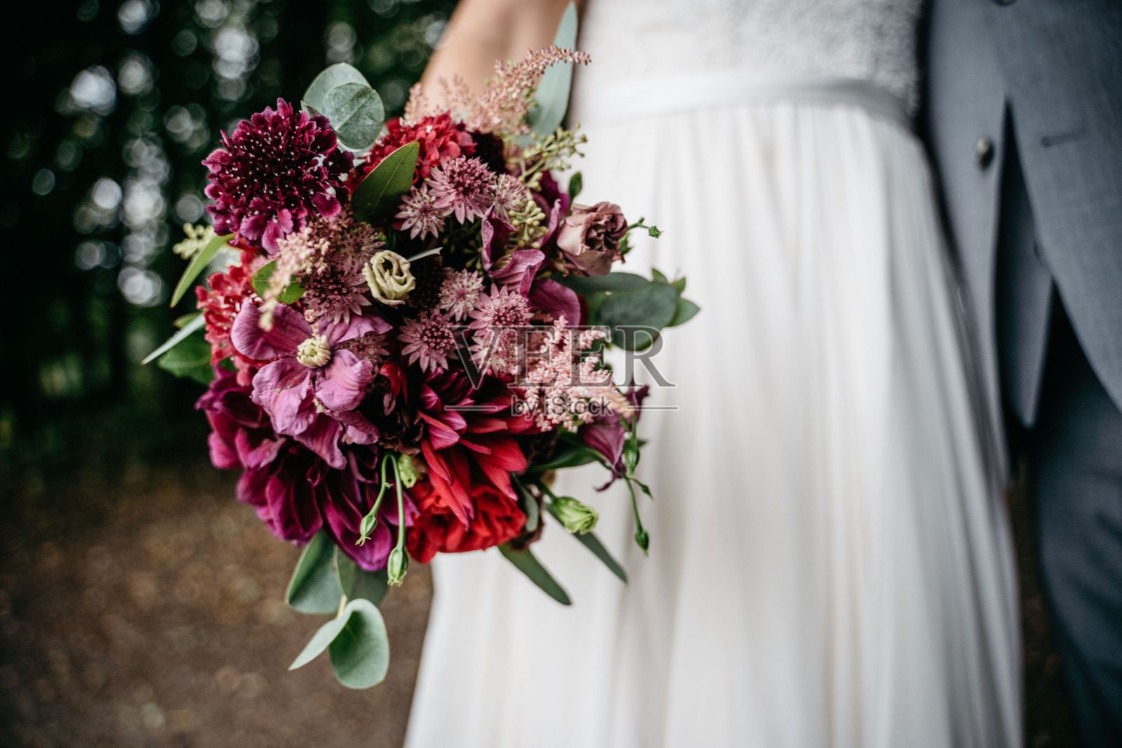 新娘在森林中手持一束鲜艳的花束。照片摄影图片