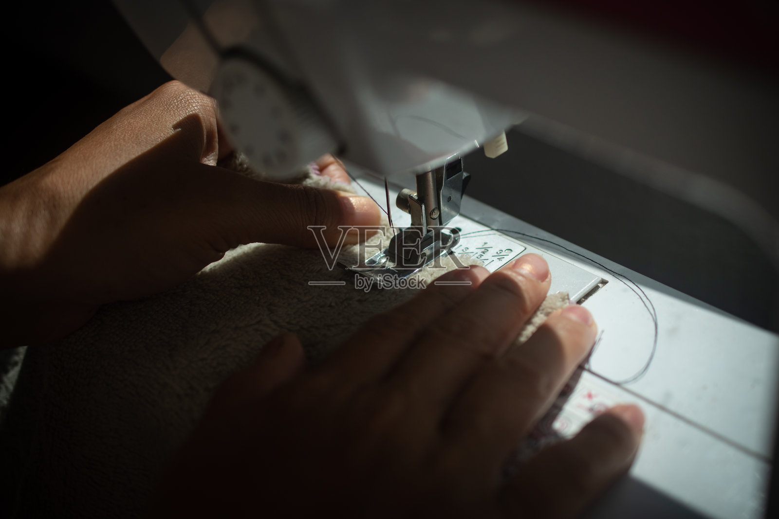 经济衰退期间，一位母亲在缝制衣服以节省开支照片摄影图片