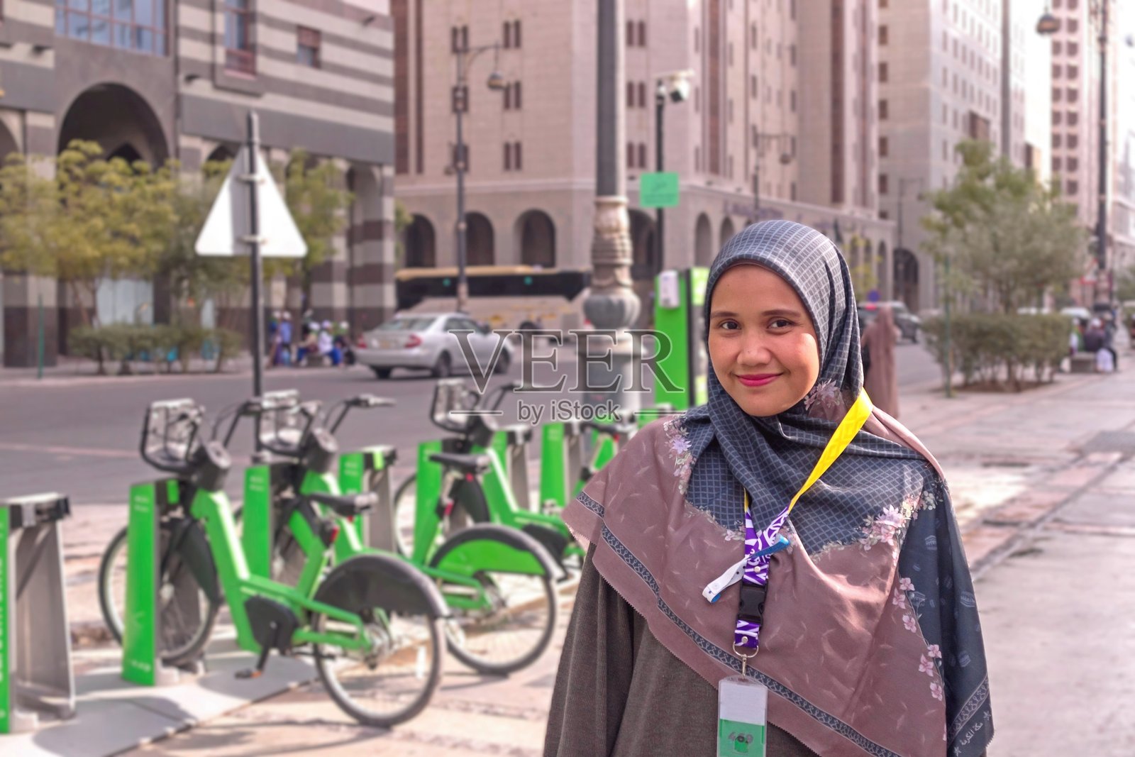 一位戴着乌姆拉朝觐者身份证徽章的亚洲穆斯林女性，在沙特阿拉伯麦地那市的街道上摆姿势。照片摄影图片