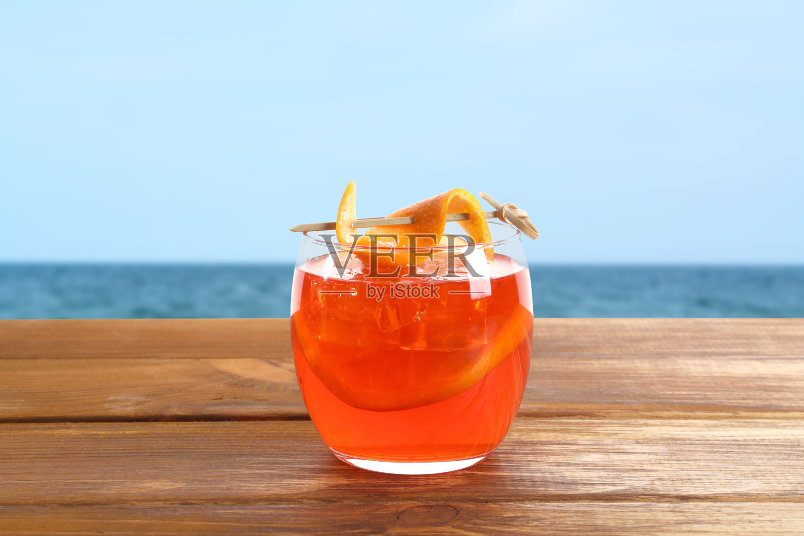 橙子片装饰的阿佩罗开胃酒鸡尾酒放在海滩的木桌上照片摄影图片