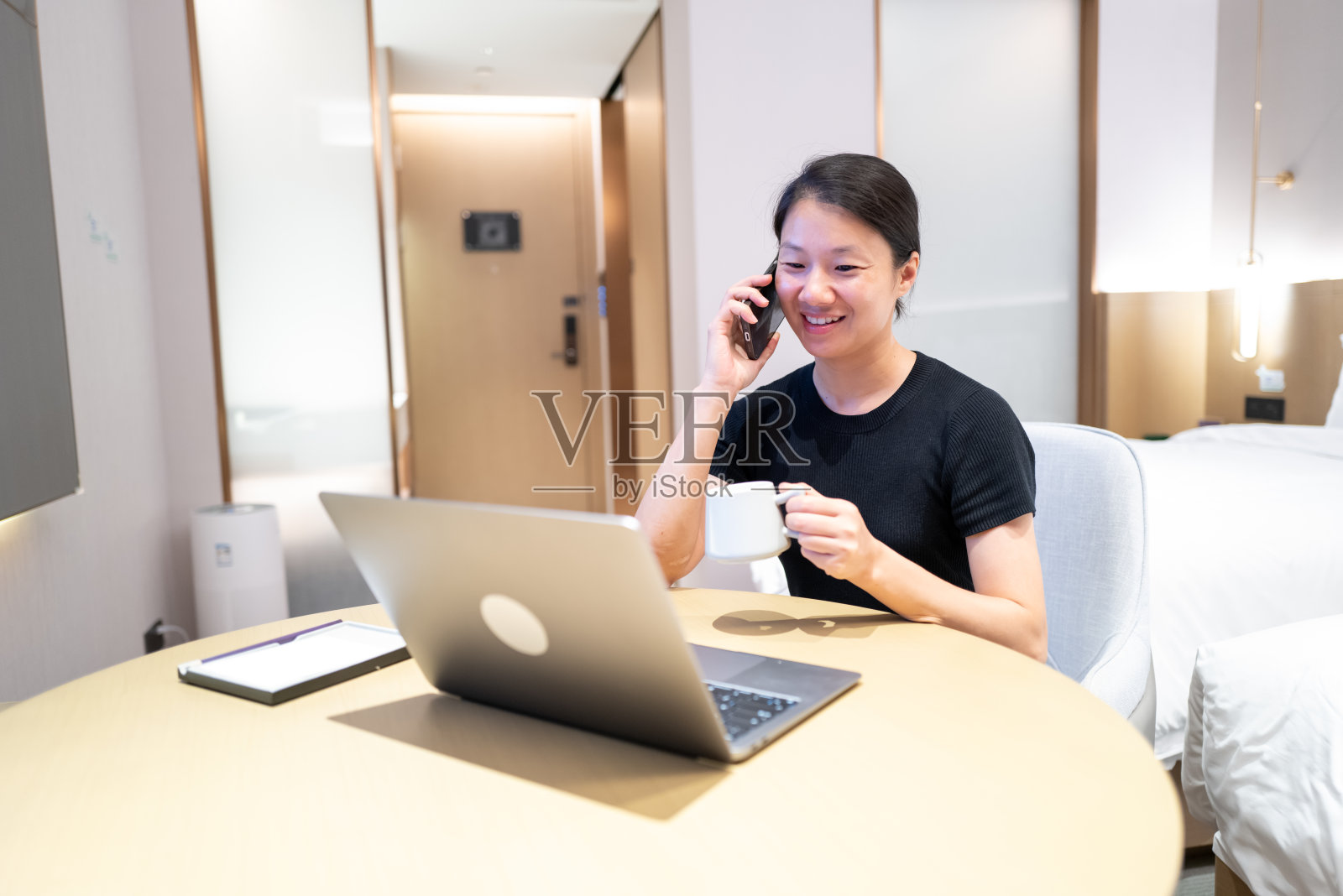 出差在酒店房间加班的中国白领女性正在使用手机照片摄影图片