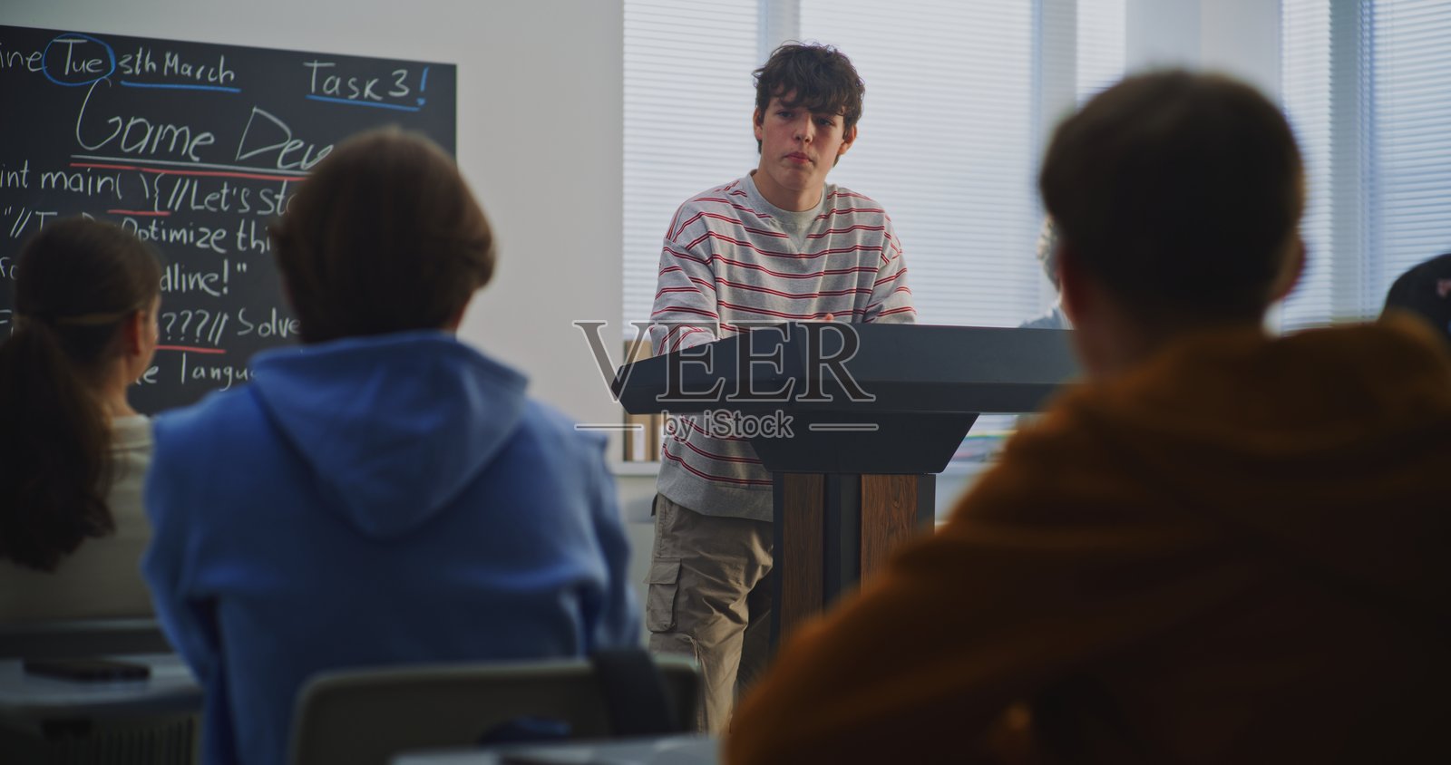 少年在讲台前解释工作，黑板上可见游戏开发主题照片摄影图片