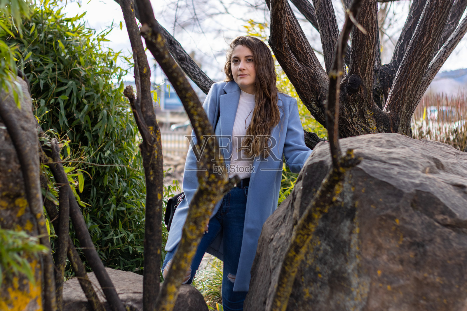 身穿蓝色外套的年轻女子在大自然中摆姿势照片摄影图片