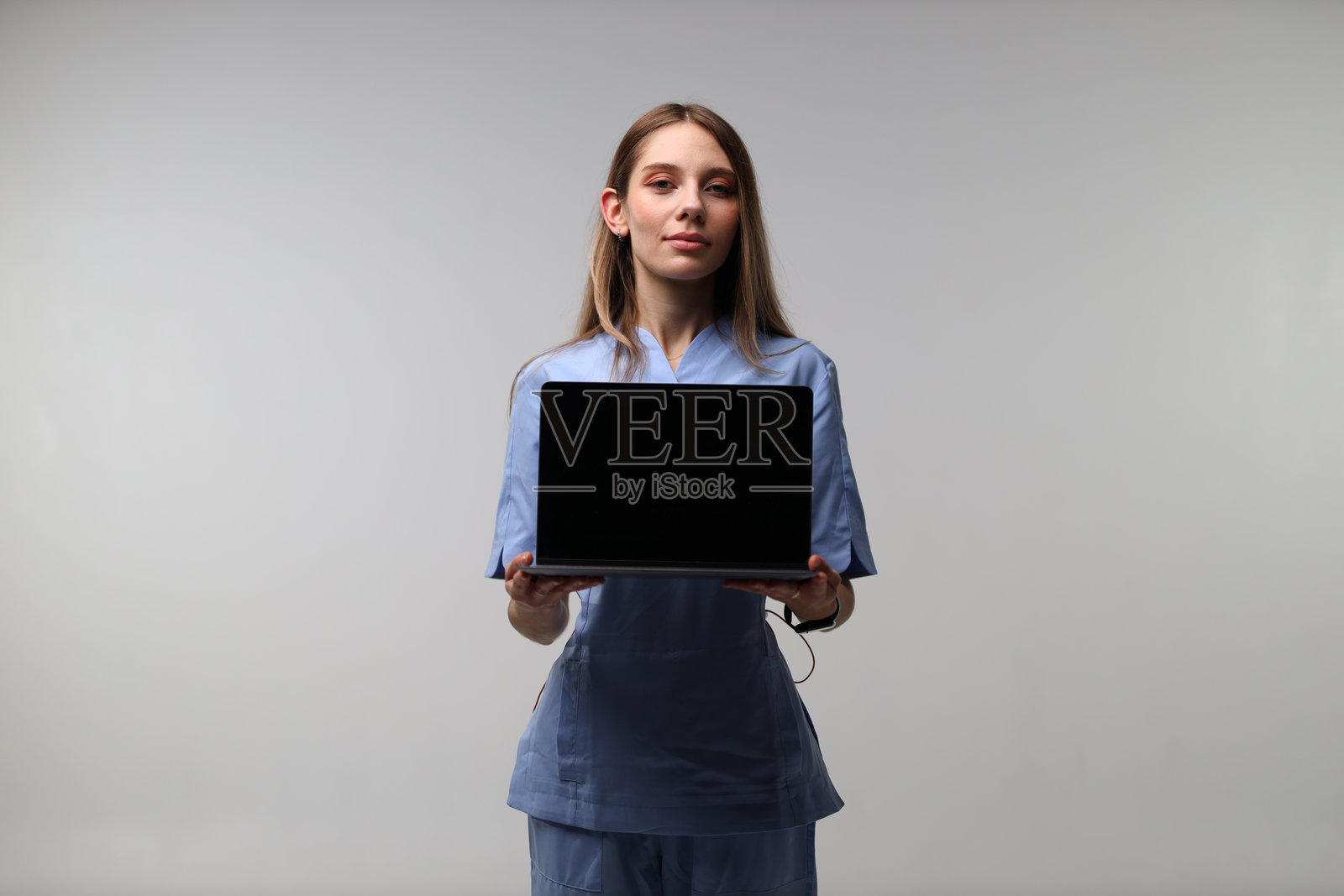 年轻的高加索女性护士展示带有空白屏幕的笔记本电脑照片摄影图片