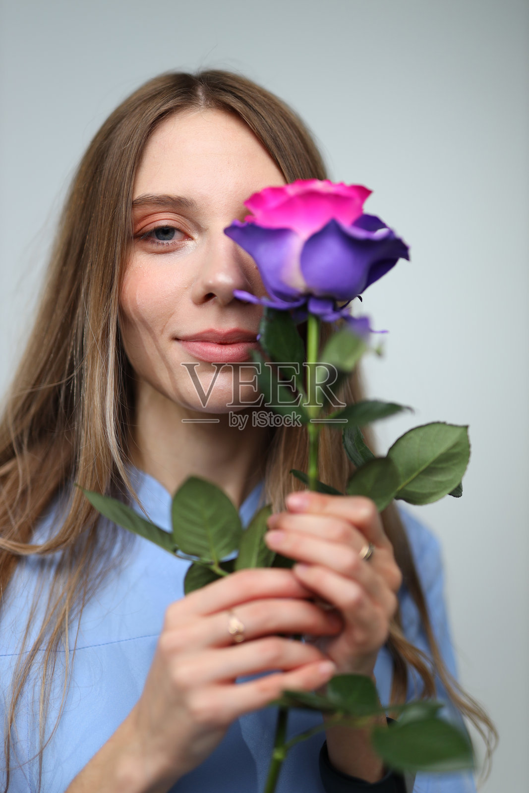 一位年轻的高加索女性，表情温柔，手持粉色和紫色的玫瑰照片摄影图片