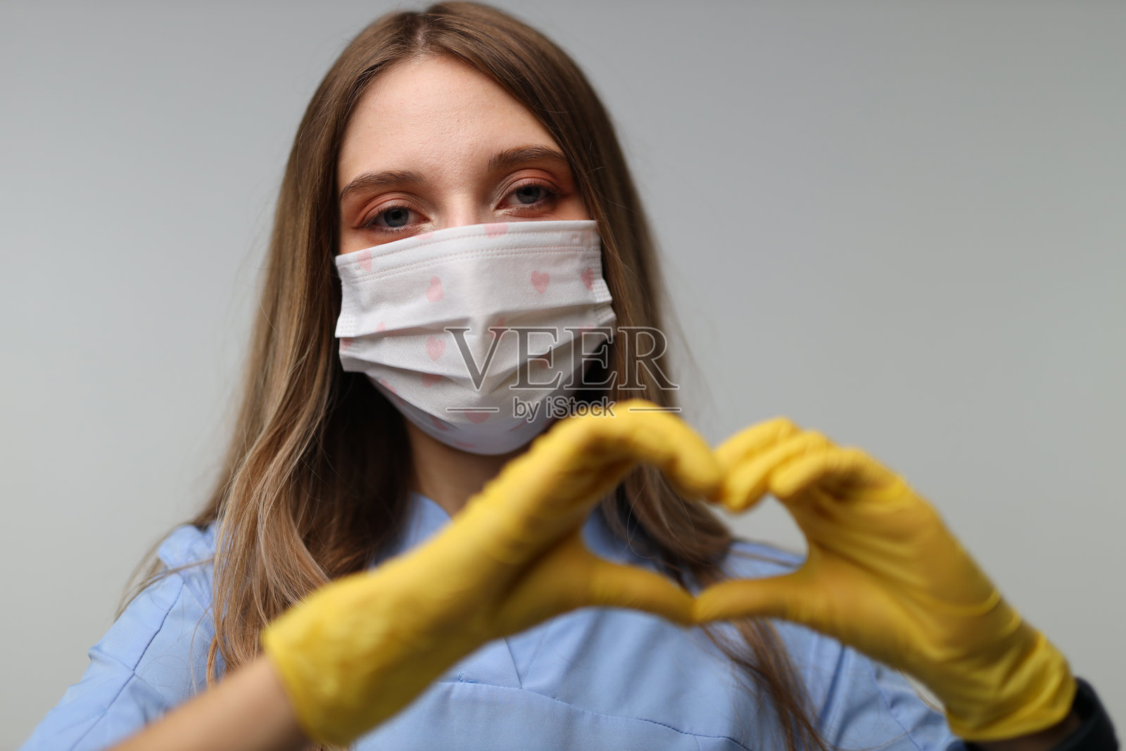 年轻的高加索女性护士用戴手套的手做出心形手势照片摄影图片