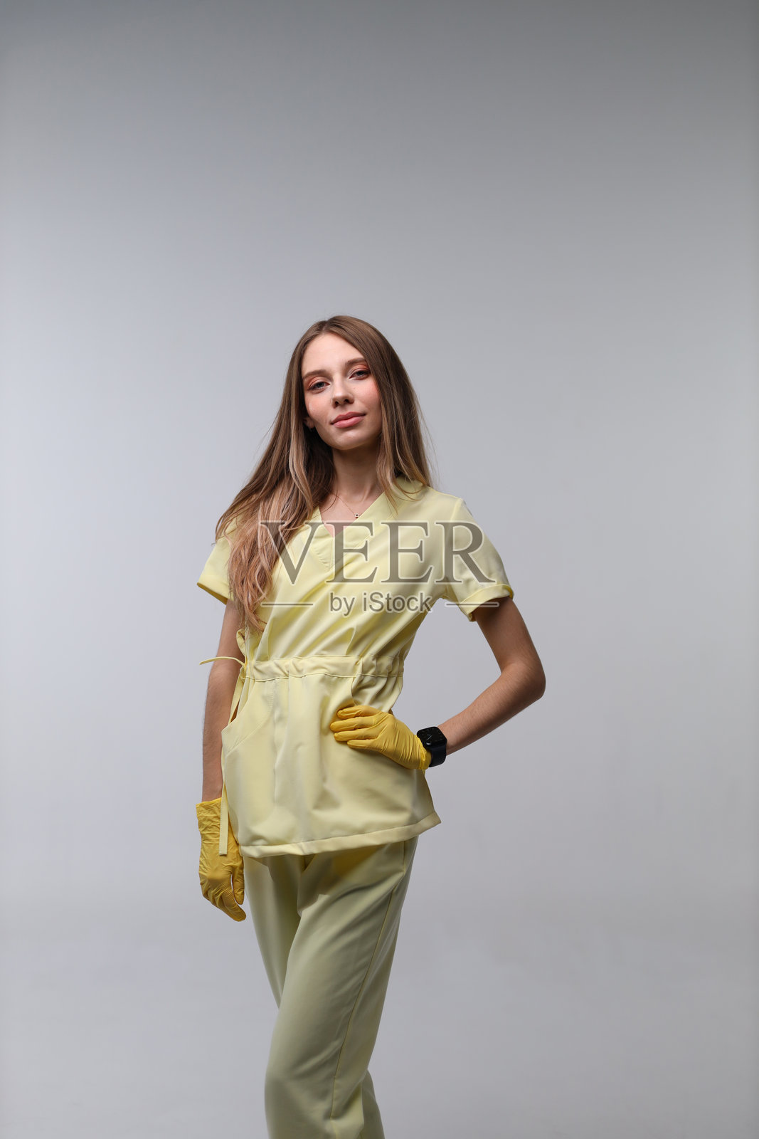 穿着手套、留着长发的年轻女子身穿黄色服装，在影棚内照片摄影图片