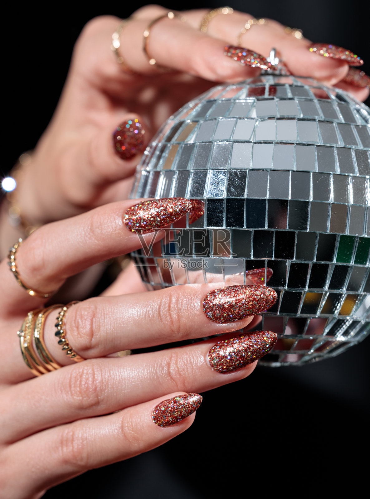 女人拿着迪斯科球的双手，手中拿着一个闪亮的大迪斯科球照片摄影图片