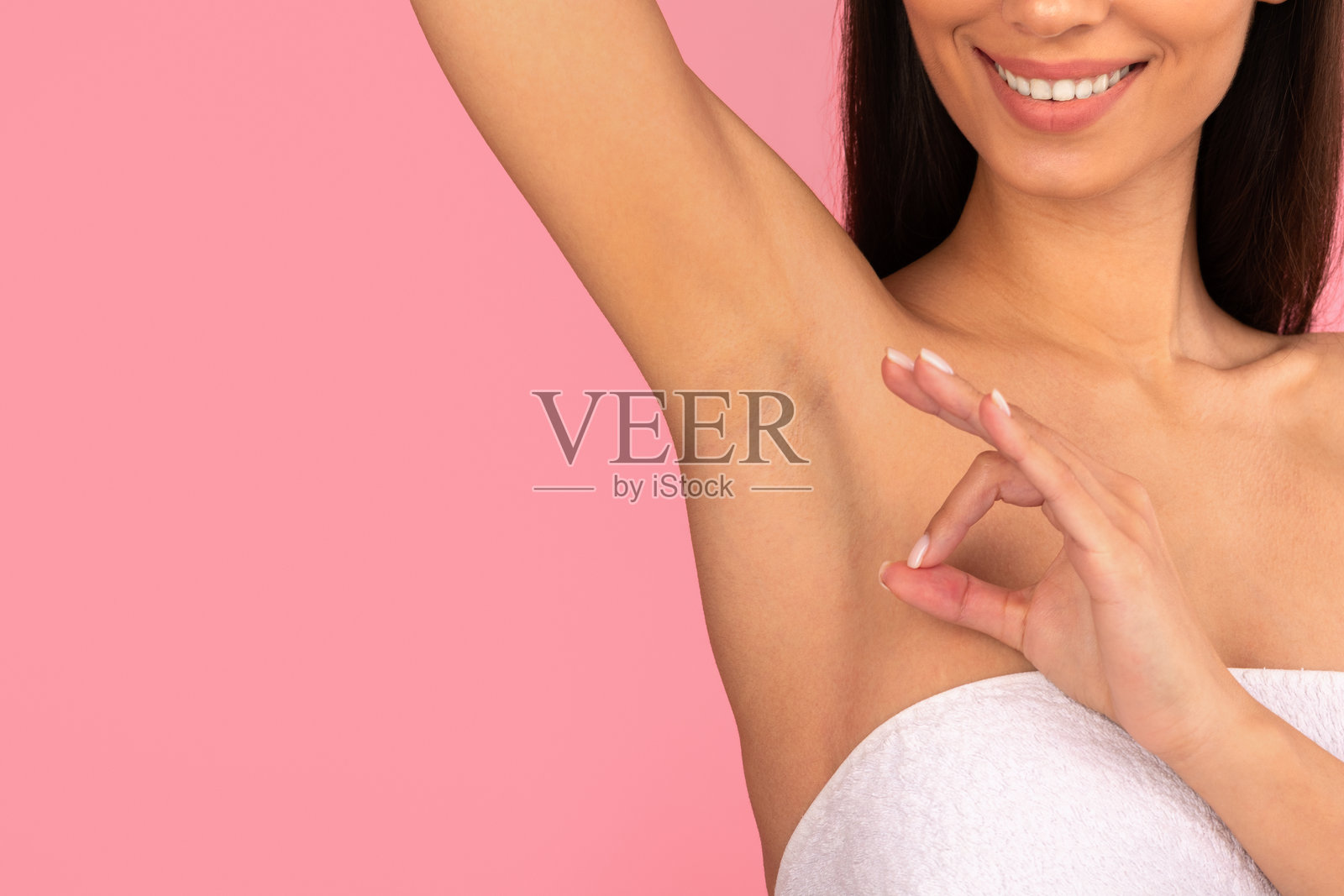 脱毛后，一位年轻女子微笑着抬起手臂，展示光滑的腋下肌肤照片摄影图片