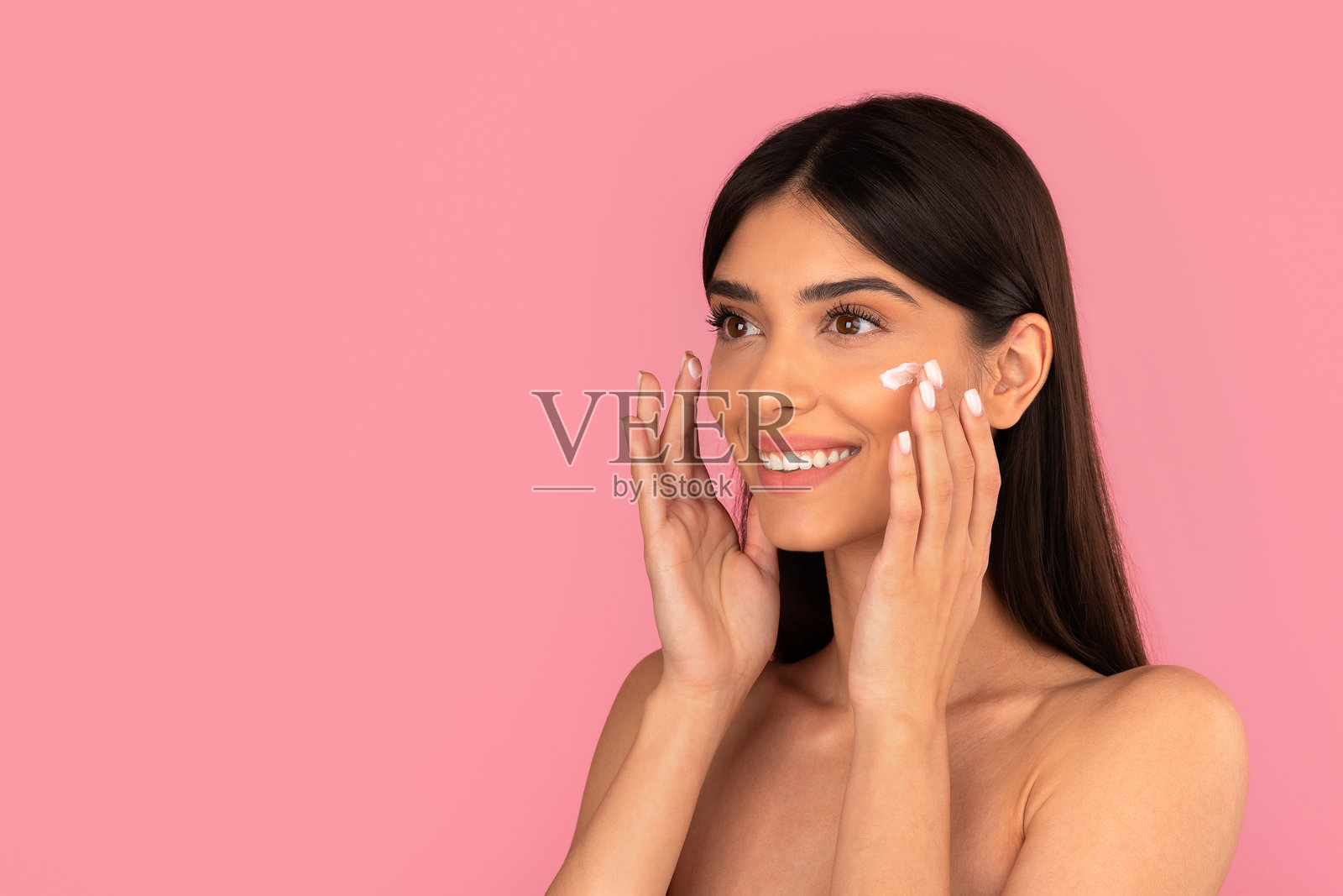 美丽的女子微笑着在脸上涂抹保湿霜照片摄影图片