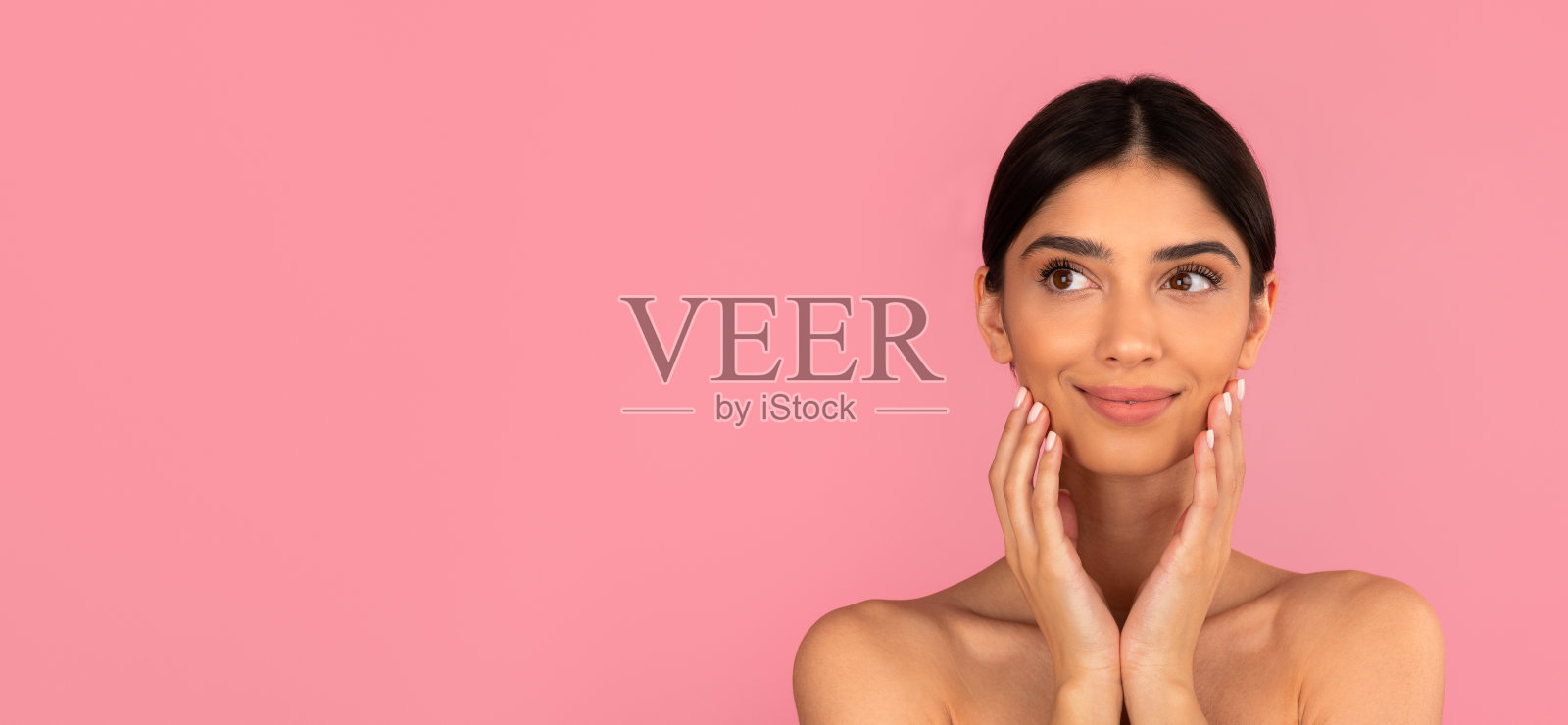 美丽的年轻女子用柔软的手触摸脸颊，并露出淡淡的微笑照片摄影图片