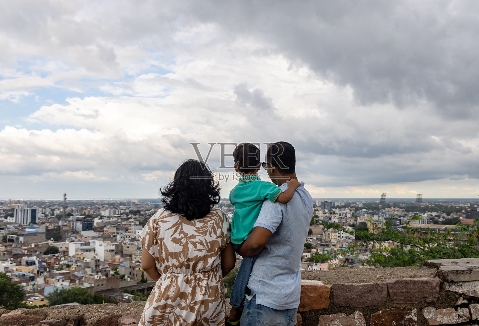 一家人在多云的季风天空下，在山顶欣赏全景城市景观，享受美好时光照片摄影图片