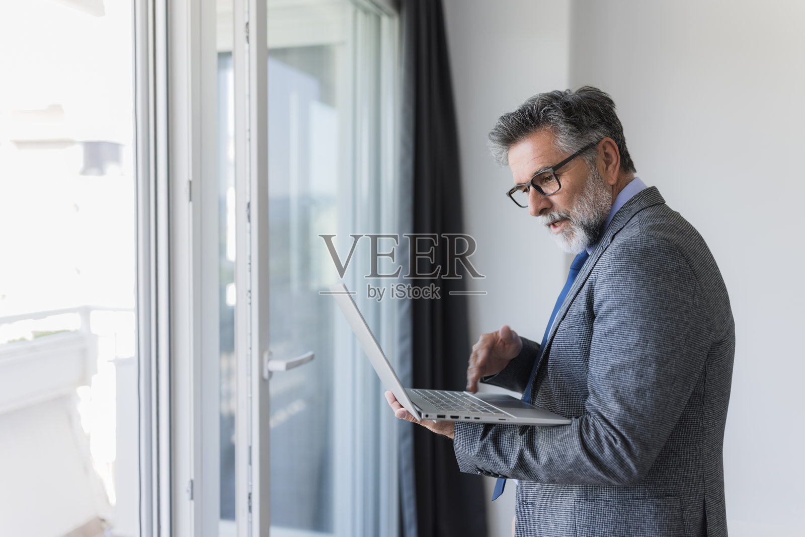 商务人士在办公室靠窗的笔记本电脑上工作照片摄影图片