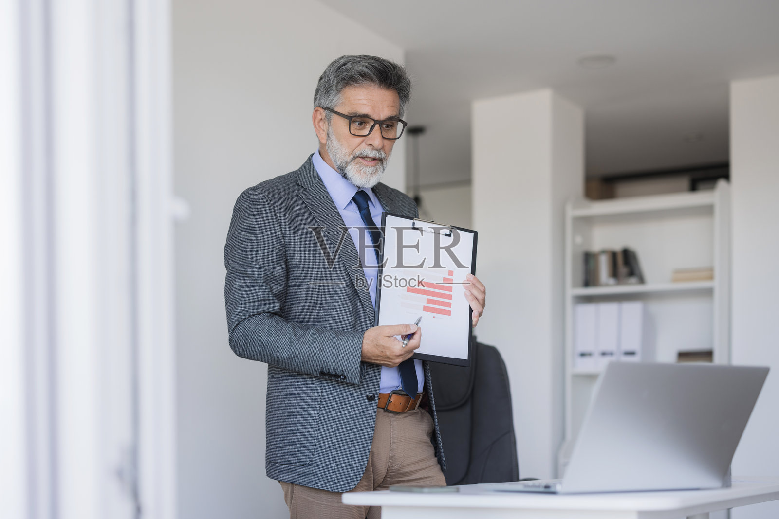一位年长的商人正在视频会议中展示图表照片摄影图片