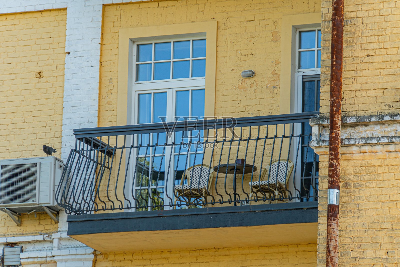 城市建筑中，带有黑色栏杆的阳台，配有白色窗框的窗户和一扇门，窗外是灰蒙蒙的天空。画面色调沉稳，着重于建筑细节。照片摄影图片