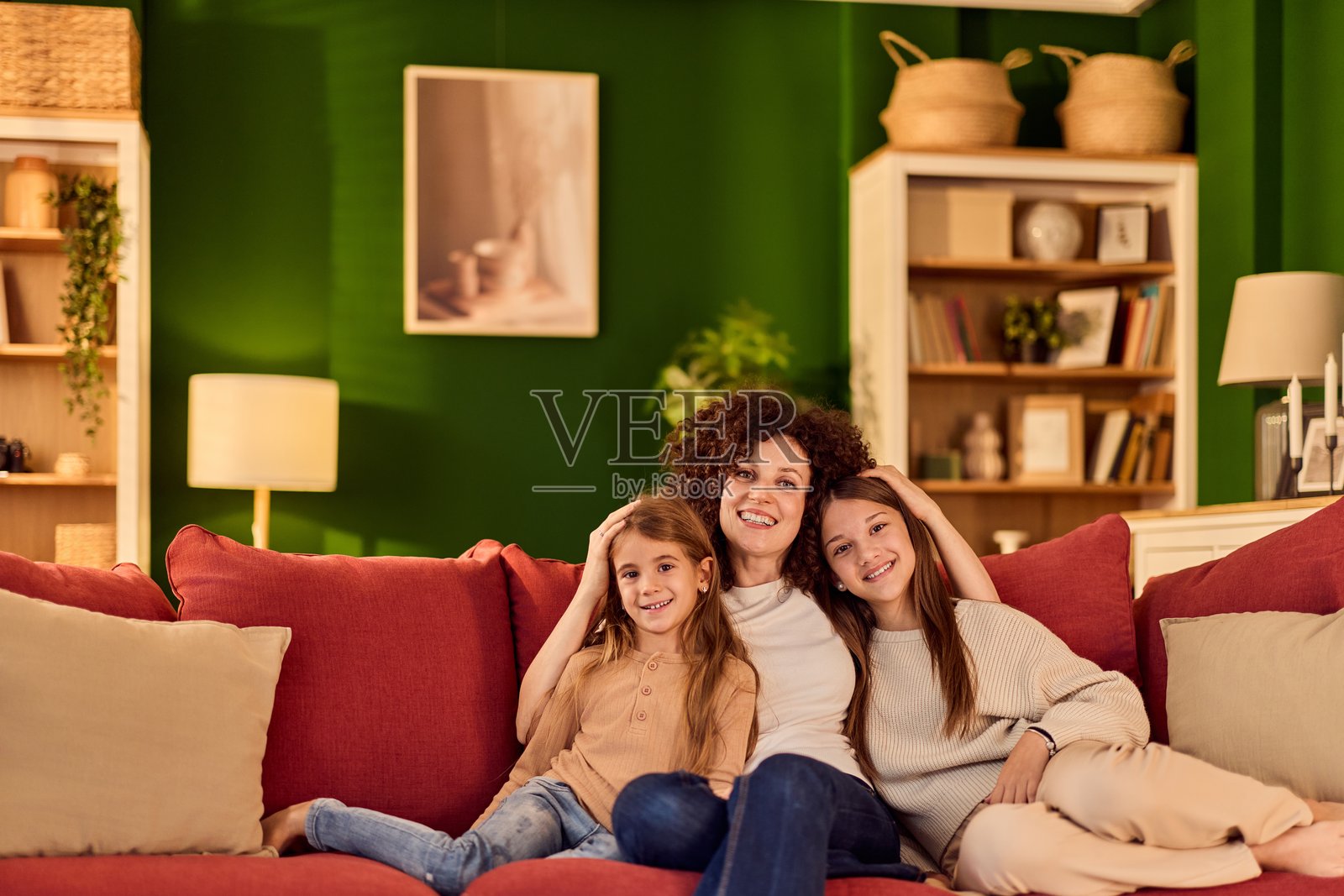 快乐的一家，妈妈和女儿们在舒适客厅的红色沙发上放松照片摄影图片