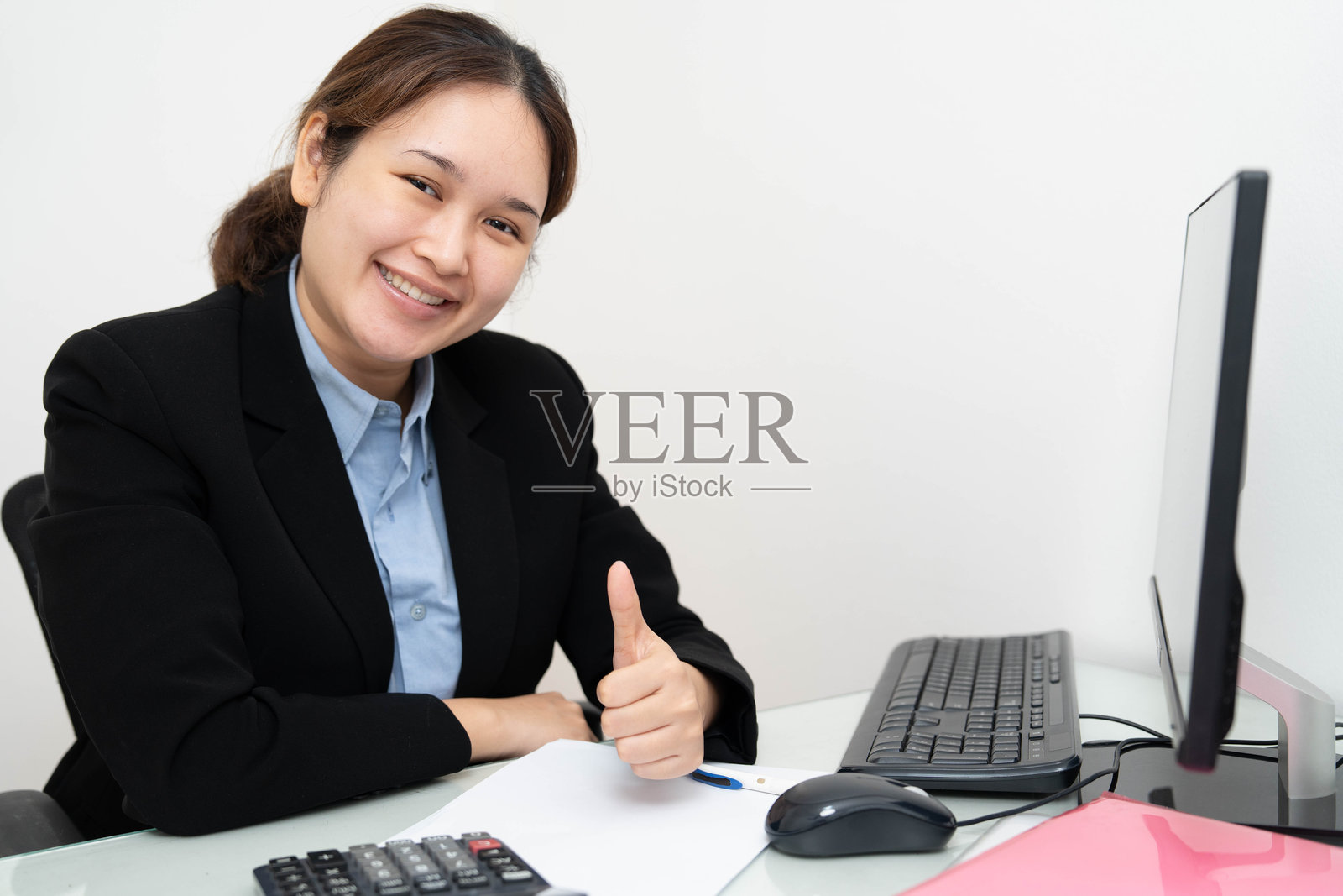 亚洲女商人对着个人电脑竖起大拇指，会计师，企业家，经理。照片摄影图片