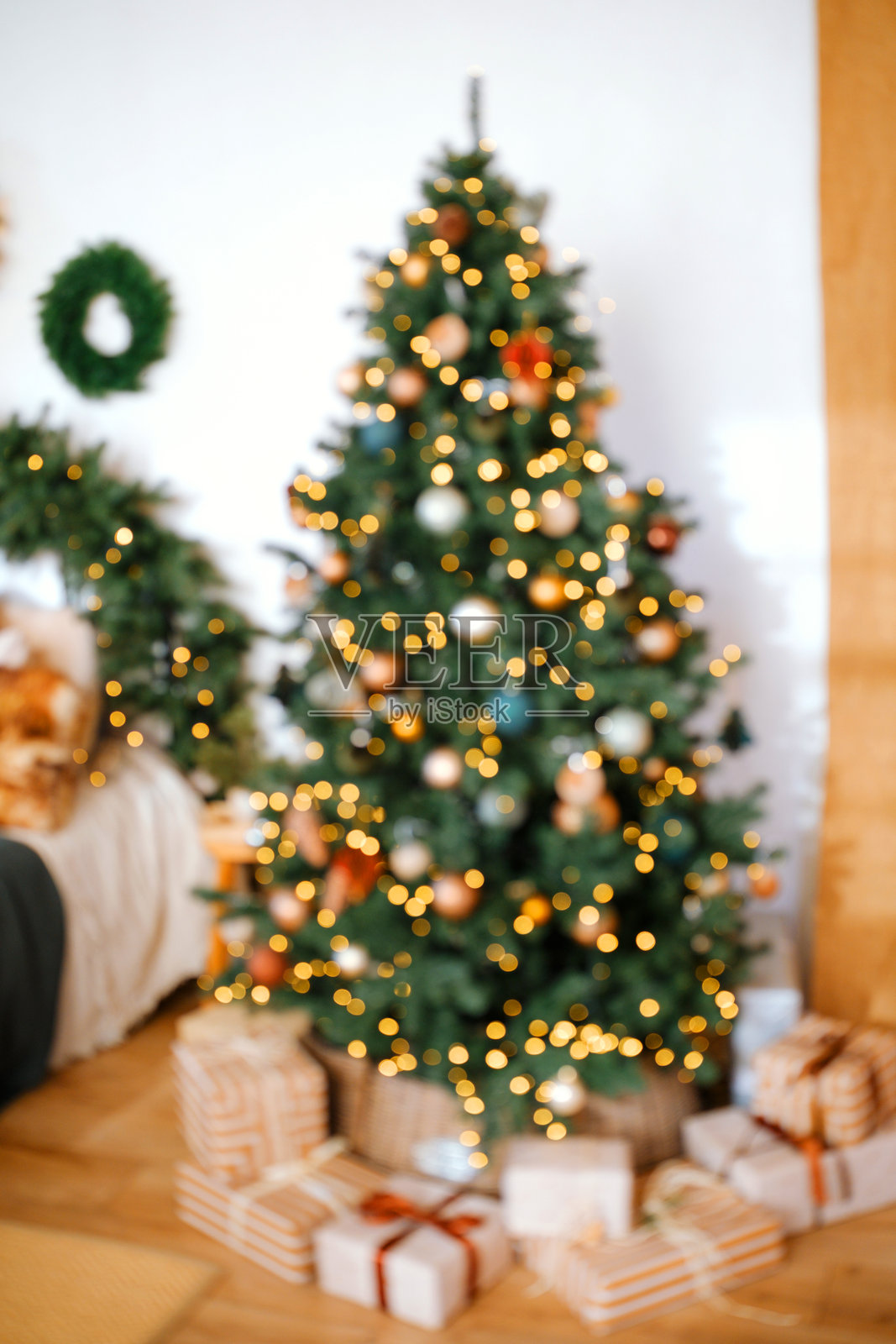 装饰一新的常青树，闪烁的灯光和礼物环绕在它周围的地板上。照片摄影图片