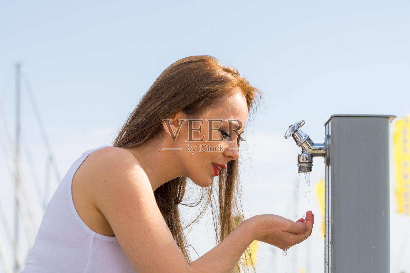 女子在街边水龙头处饮水照片摄影图片