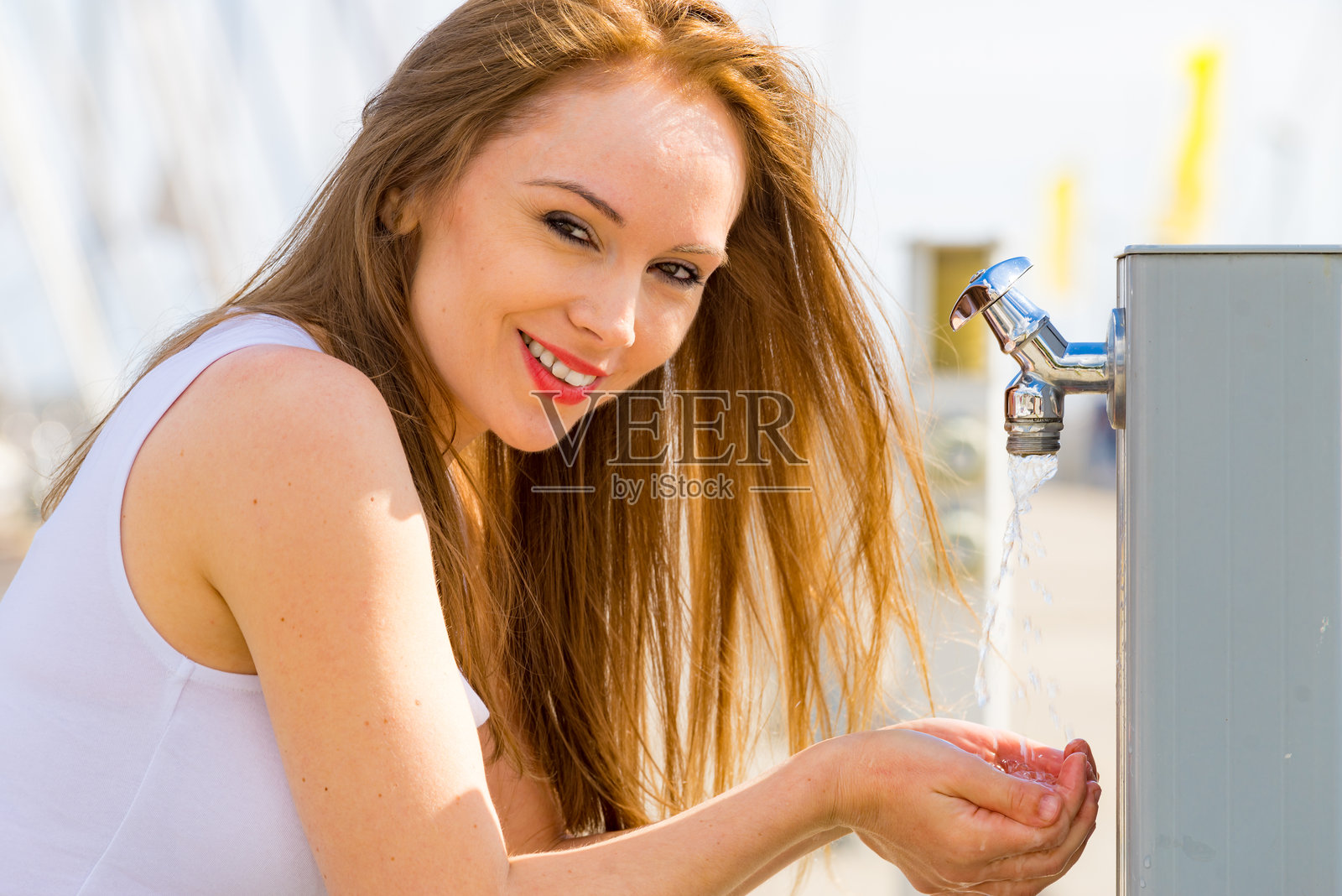 女人在街边水龙头处喝水照片摄影图片