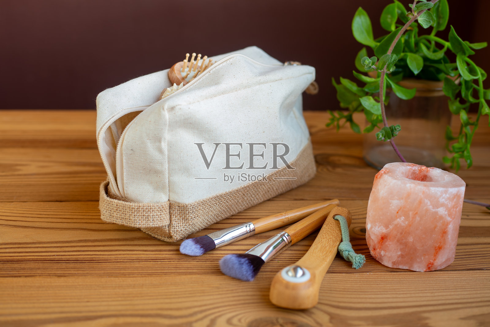 木质背景上的天然亚麻化妆包，配有盐晶烛台、用于面部焕活按摩的木质滚轮和竹制化妆刷。一种零浪费的美妆理念。照片摄影图片