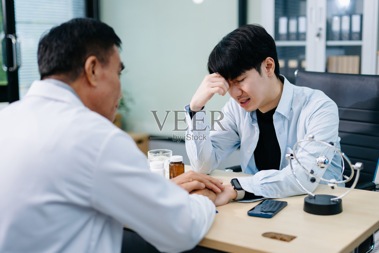 年轻亚裔男性在办公室与精神科医生讨论心理健康。情感支持、焦虑、治疗和富有同情心的护理。照片摄影图片