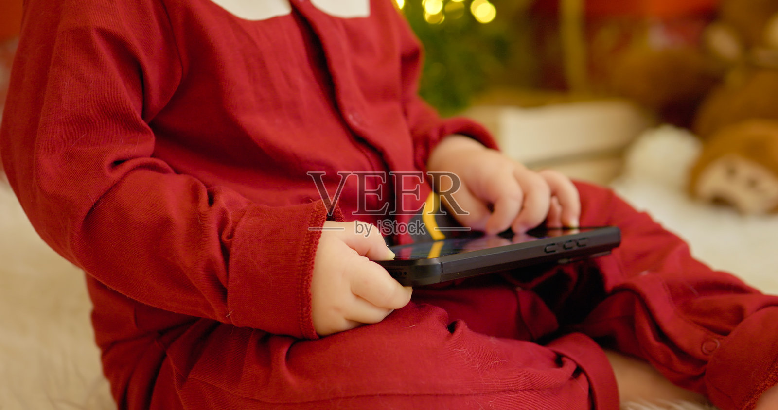 小男孩在节日季的圣诞树旁玩智能手机照片摄影图片