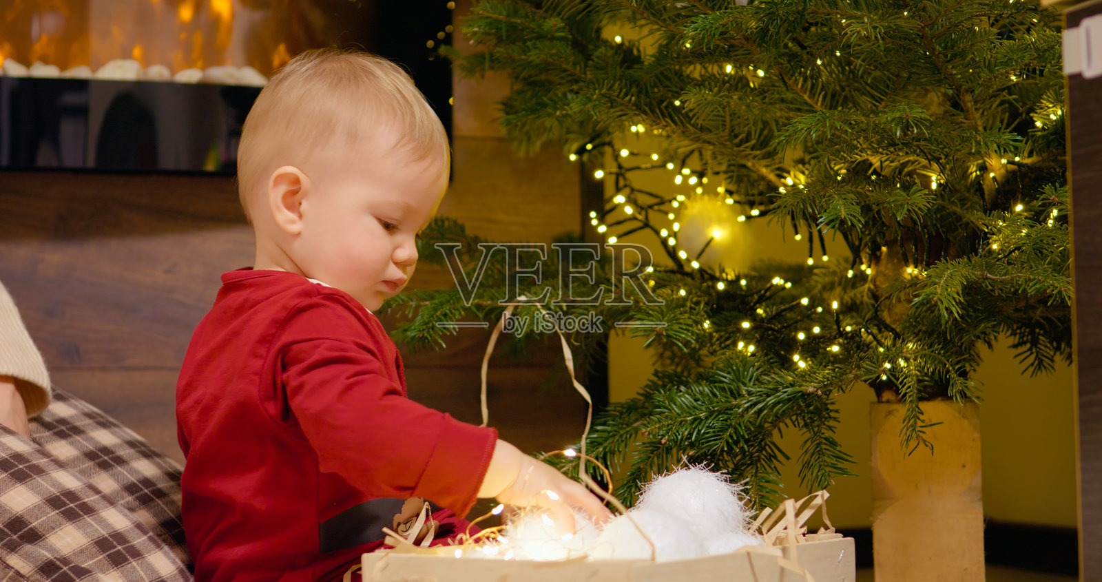 母亲指导孩子在装饰精美的圣诞树上摆放色彩缤纷的圣诞球照片摄影图片