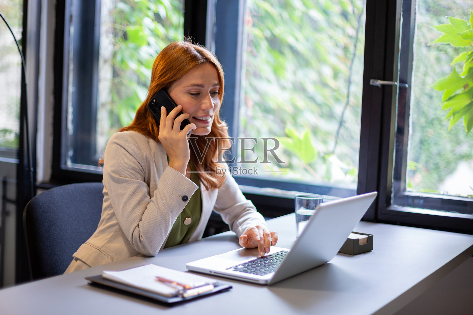 女商人一边打电话一边用笔记本电脑打字照片摄影图片