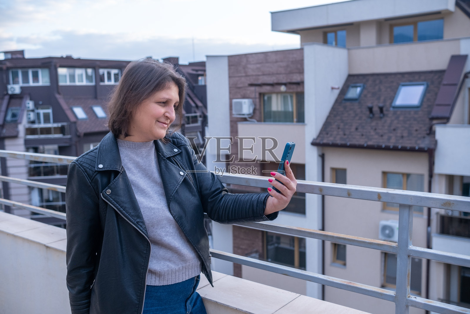 女人在城市阳台上使用智能手机的场景照片摄影图片
