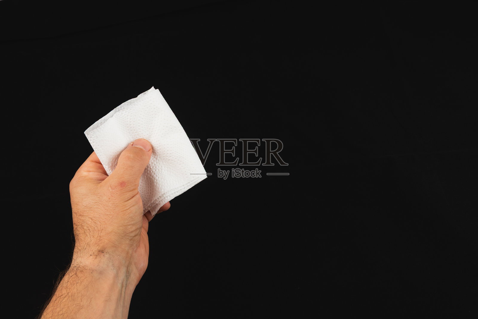 一只手拿着一张白色的餐巾纸，背景是黑色的照片摄影图片
