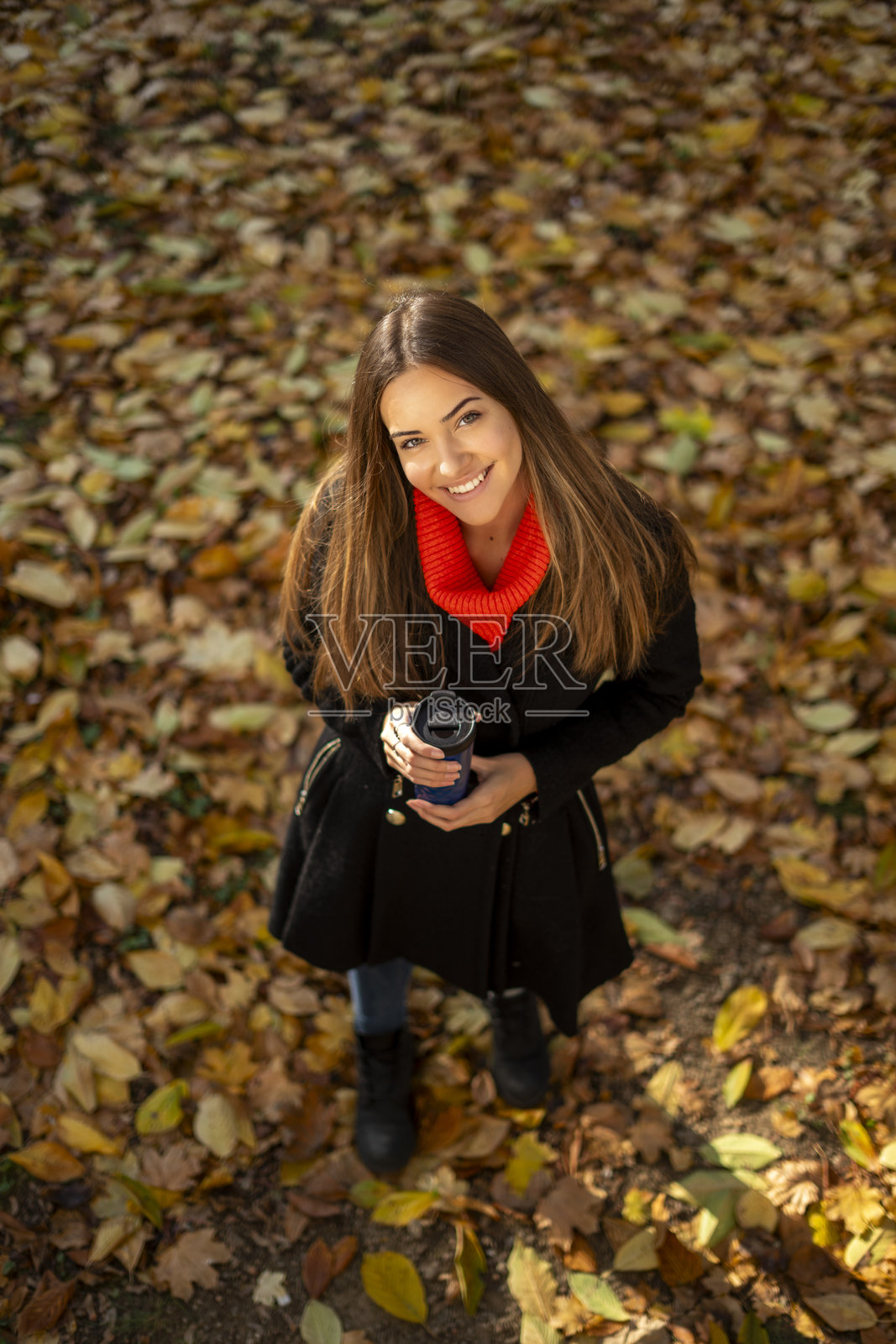 微笑的女士手持咖啡杯，享受着秋日时光照片摄影图片