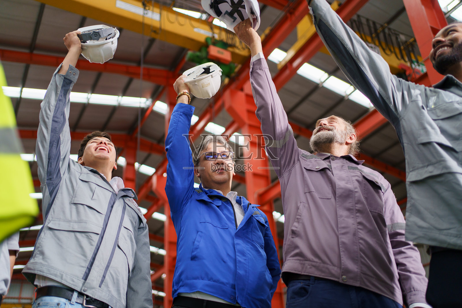工程师团队自豪地将头盔举在一起，象征着团结。照片摄影图片