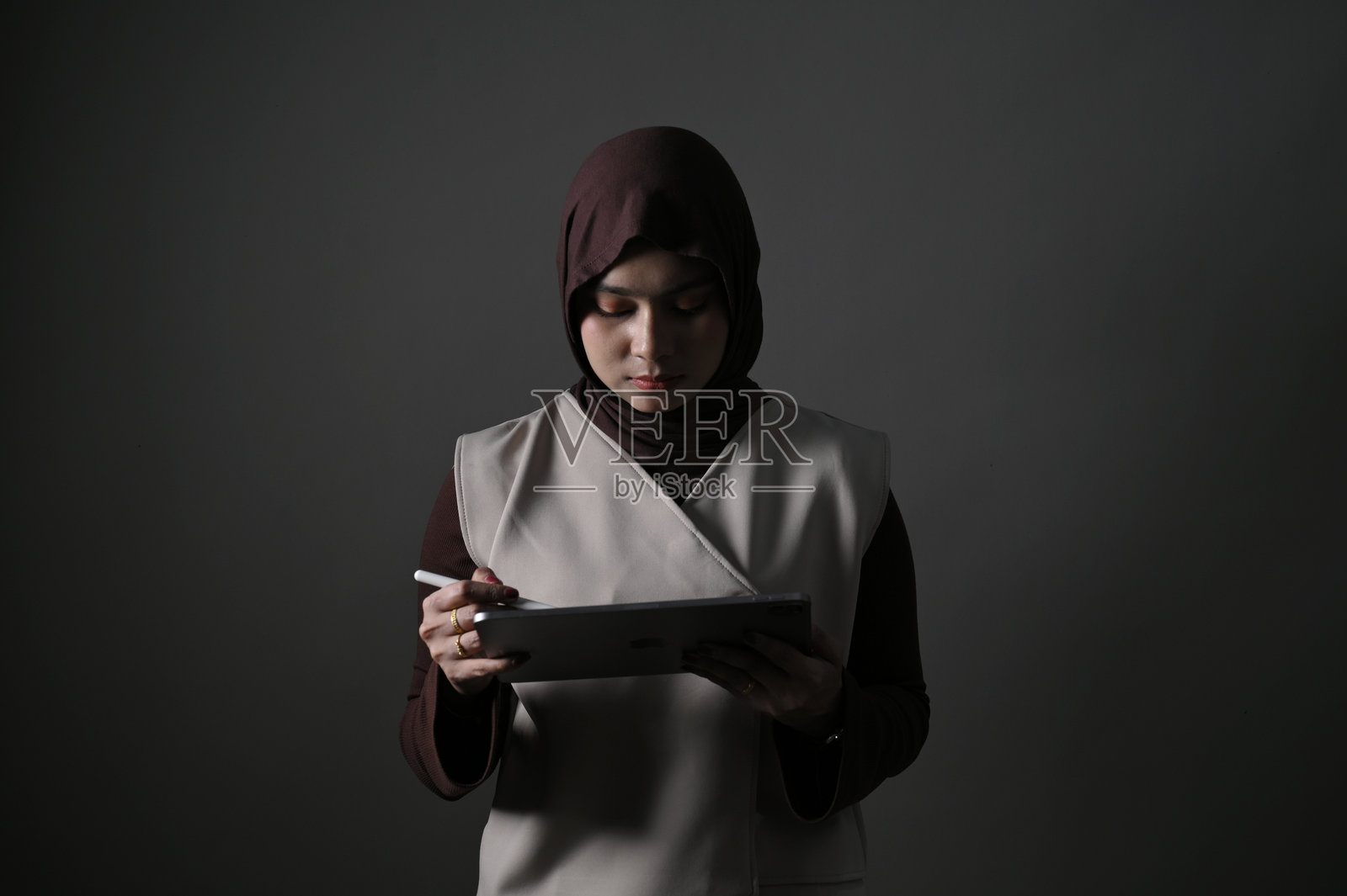 肖像摄影棚拍摄亚洲戴头巾女性使用平板电脑照片摄影图片